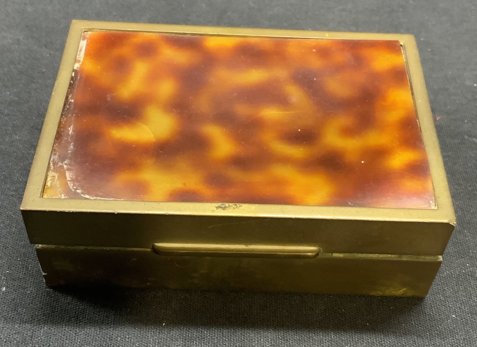 Vintage Brass Marbled Lid Box: Vintage brass box with marbled brown and tan toned lid. Possibly cellulose. Measures approx. 3.75 x 2 5/8 x 1.25 inches. Surface wear including scratching and warping observed. Vintage box, brass box,