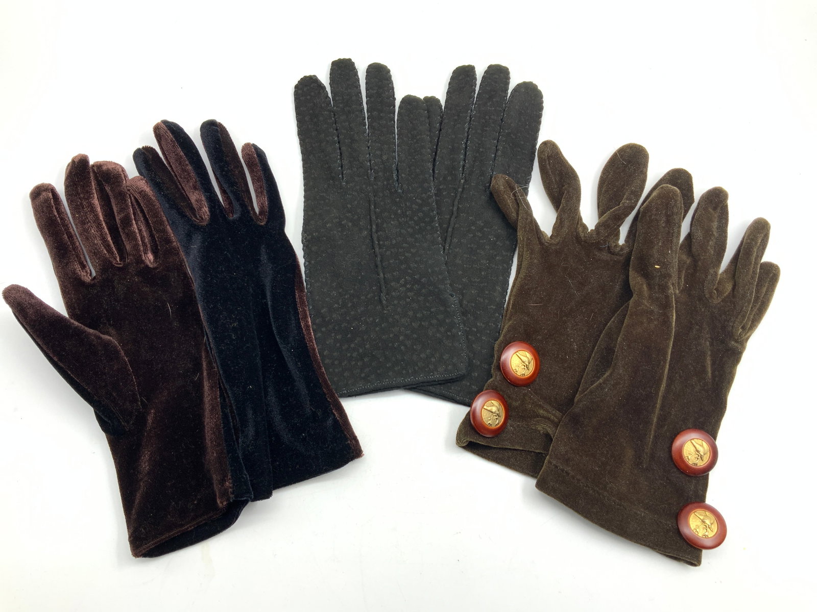 Lot 3 Velvet & Leather & More Gloves: Lot of 3 pairs of gloves. 1 velvet style gloves, marked 100% Polyester, with brown and black tones. 1 pair of suede leather gloves and another pair of velvet style gloves with red and gold toned butto