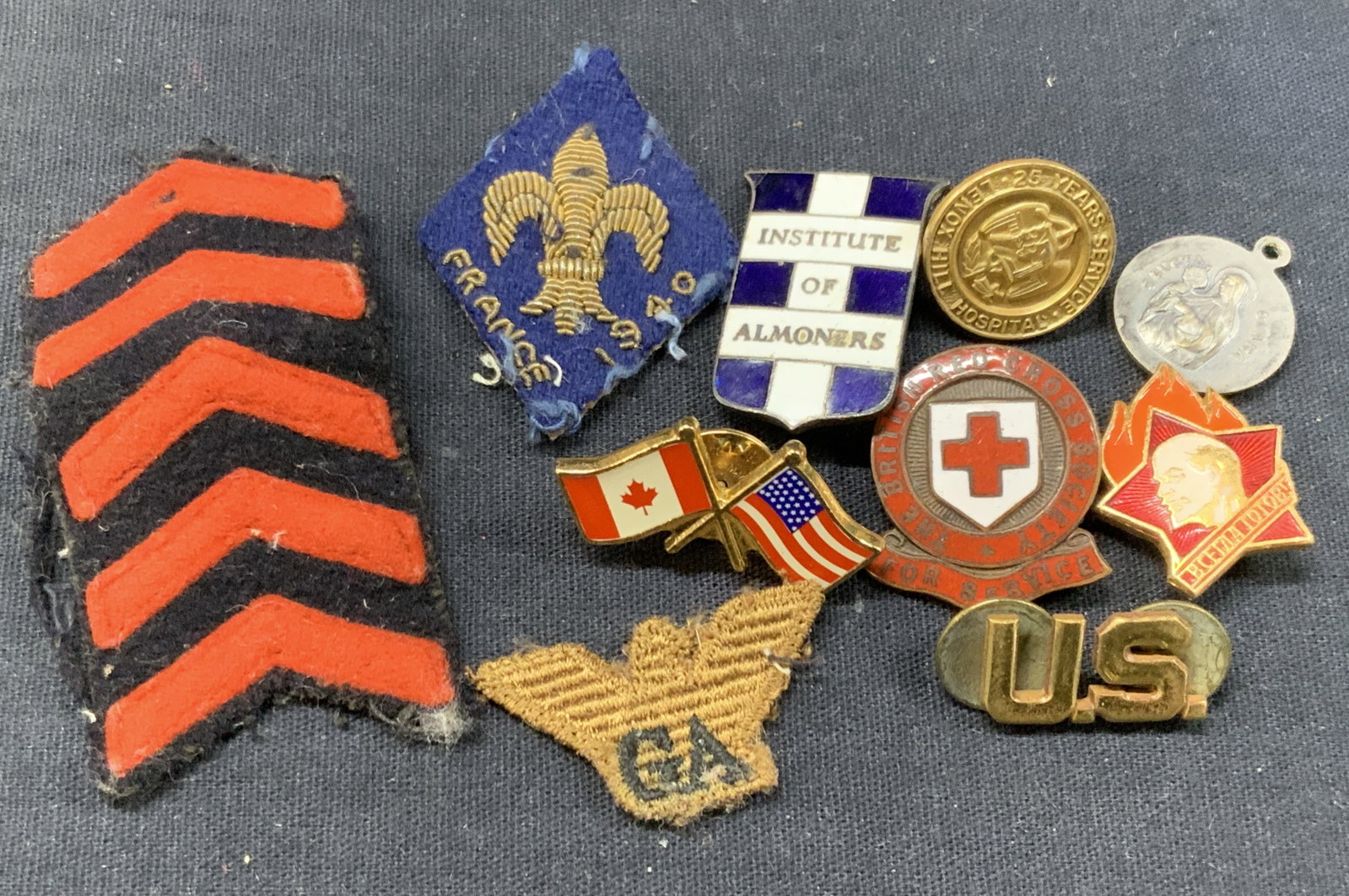 Lot 10 Vtg Military & Hospital Pins & Patches: Lot of 10 vintage patches and lapel pins. 3 military patches, 1 embroidered with a Fleur de lis marked France, 1 eagle patch with the initials. GA. 1 enamel pin from the Institute of almoners, and the