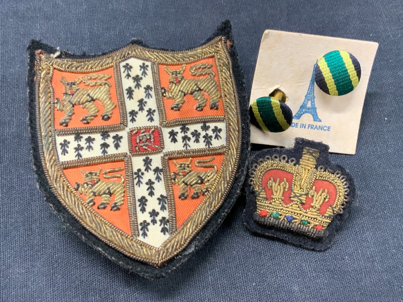 Lot 3 Embroidered & Sewn Pins & Cufflinks: Lot of 3 pins and cufflinks. 1 embroidered pin depicting the Shield from Cambridge university with embroidered lions and outer edges. Approx 3.25 x 2.75 inches. 1 embroidered crown pin patch and a pai