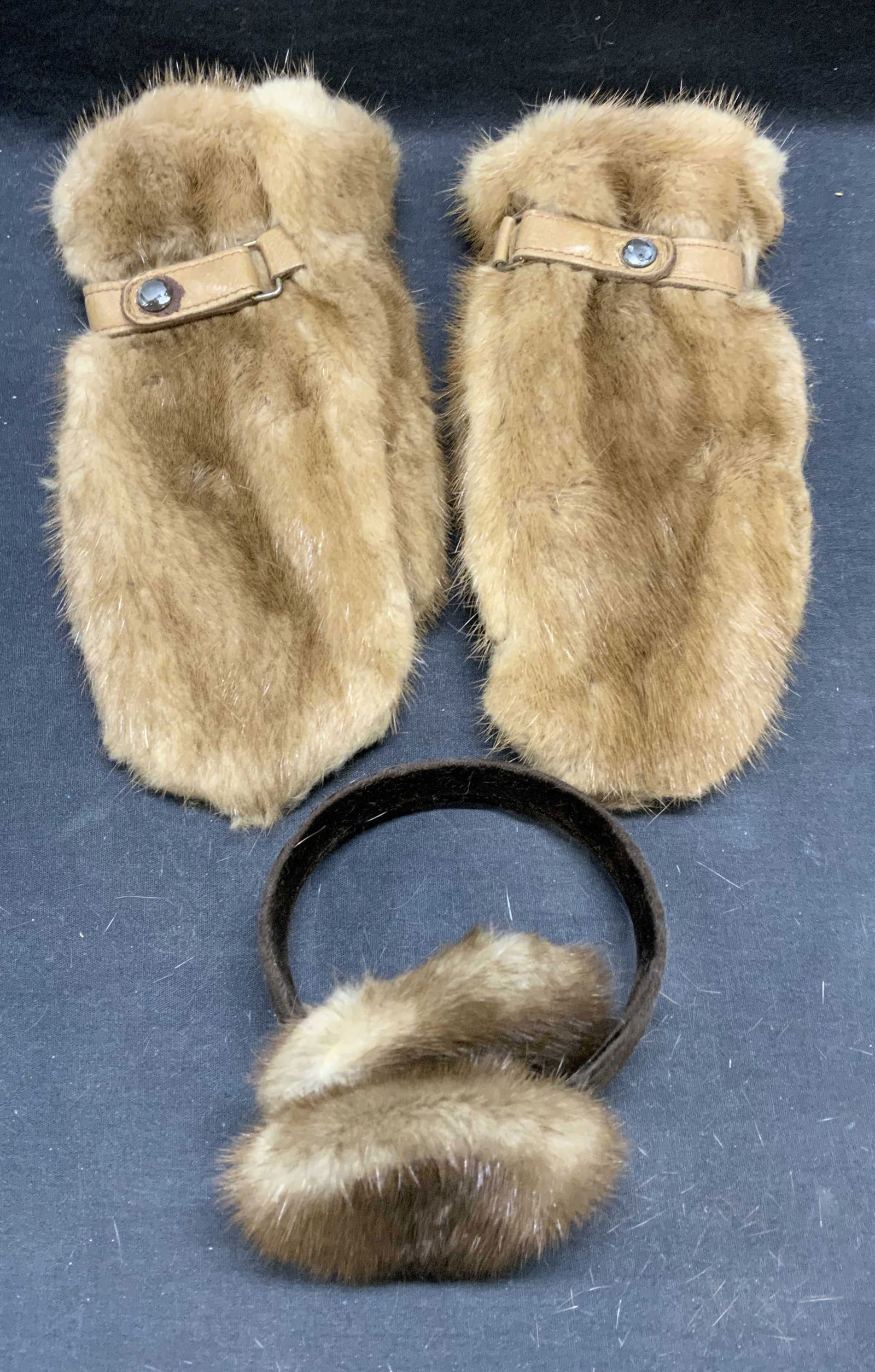 Lot 2 Tan Mink Fur Gloves & Earmuffs: Lot of 2 pieces. Tan mink fur gloves and brown mink fur earmuffs. Gloves measure approx. 10.5 inches long. Earmuffs measure approx. 7 inches wide. Both pieces have wear to material including shedding