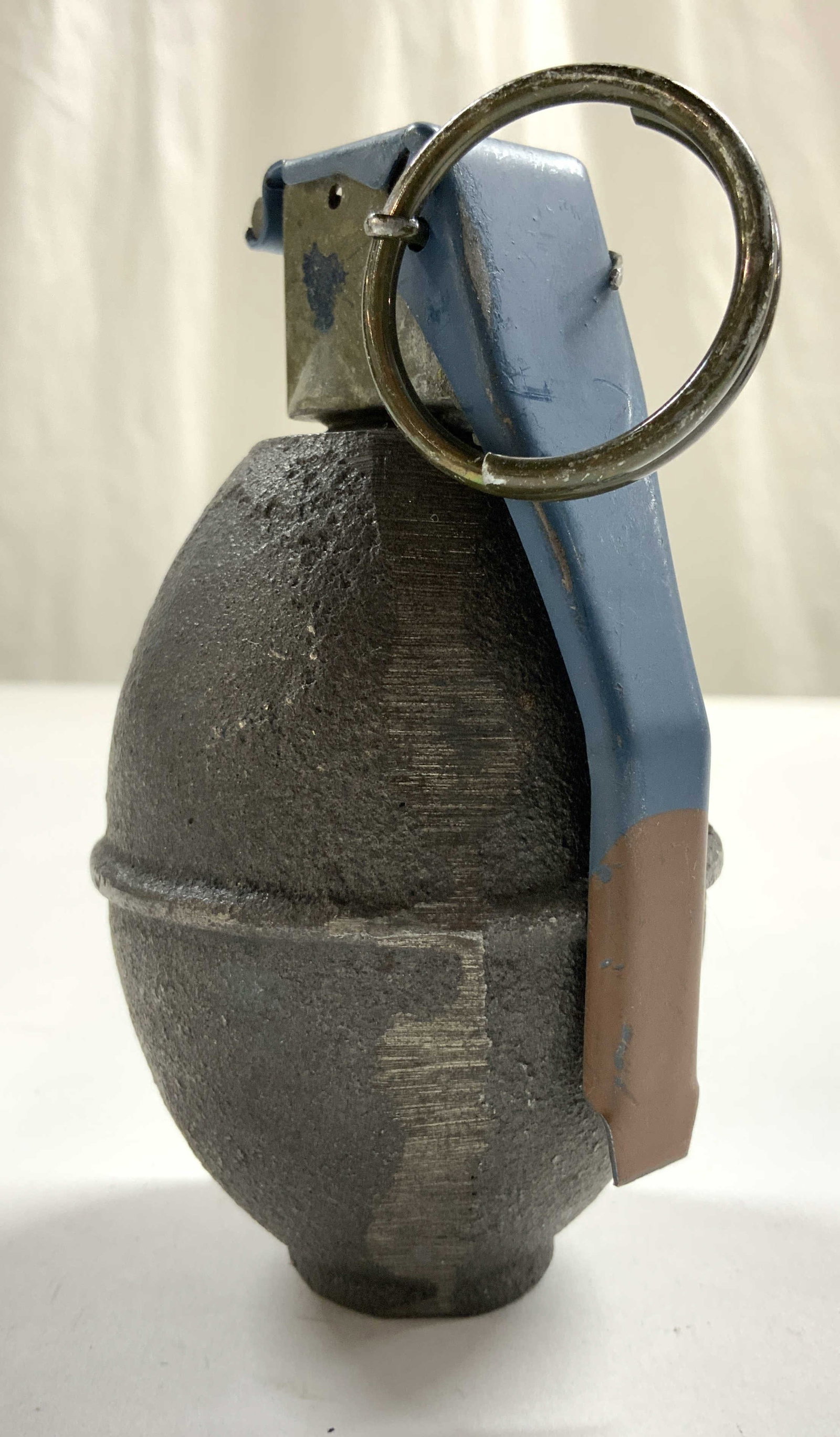 FUSE M228 Lemon Hollow Grenade Iron Paperweight: Top of piece marked FUSE M228 MEI05C 022-027. Grenade paperweight is slate with blue toned top. Interior is hollow. Appears to be iron. Piece measures approximately 4.25 inches tall 2.25 inches wide. 