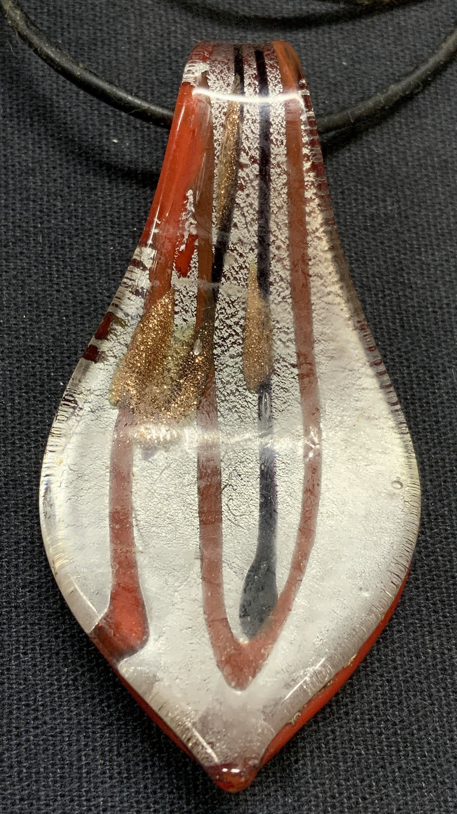 Vintage Art Glass Pendant Necklace: Vintage art glass pendant necklace. Red, silver, gold, and black tone art glass pendant on black cord. Pendant measures approx. 2.5 x 1.25 inches. Necklace drop length approx. 8 inches. Some scratchin