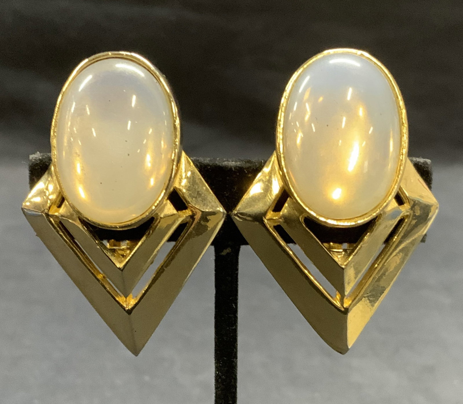 Vintage Gold Tone Moonstone Style Earrings: Vintage gold tone geometric earrings with moonstone style Cabochon. Clip on backing. Measure approx. 2 x 1 3/8 inches. Some scratching observed. Estate jewelry, costume jewelry, cocktail jewelry, fash
