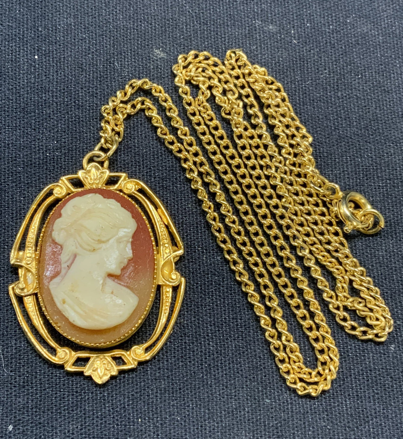 Gold Tone Cameo Pendant Necklace: Gold tone necklace with cameo pendant. Carved shell style cameo. Drop length approx. 11.5 inches. Pendant measures approx. 1 3/8 x 1 1/8 inches. Some scratching observed. Estate jewelry, costume jewel