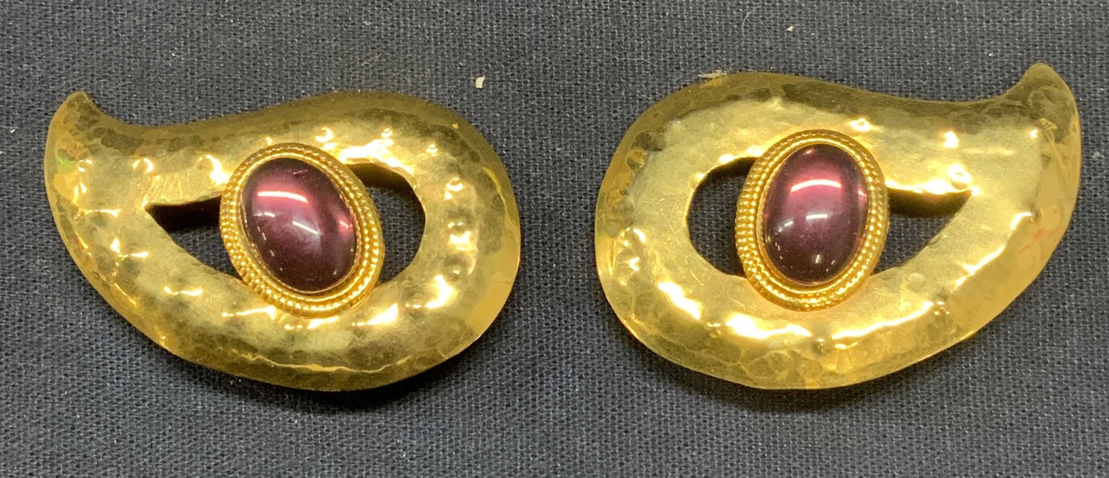 Gold Tn Paisley Purple Cabochon Earrings: Gold tone paisley shaped clip on earring sight raised dot pattern and purple tone cabochon. Measures approx. 1.25 x 2 inches. Some scratching observed. Estate jewelry, costume jewelry, cocktail jewelr