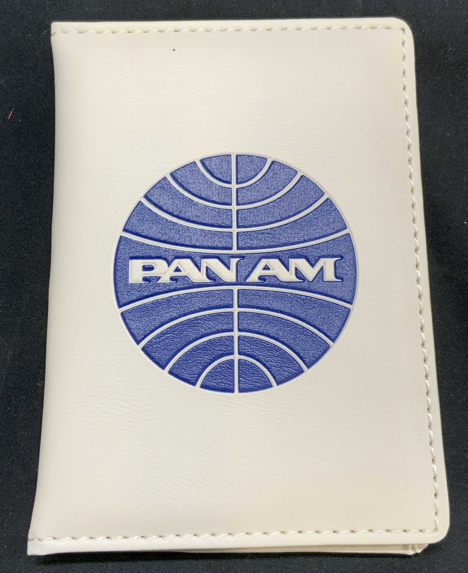 PAN AM Vintage Leather Passport Wallet: Wallet has PAN AM Trademark. Piece is white with blue toned trademark. Interior has clear pocket & 5 pockets. Appears to possibly be leather. Piece has stitching at edges. Wallet when unfolded measure