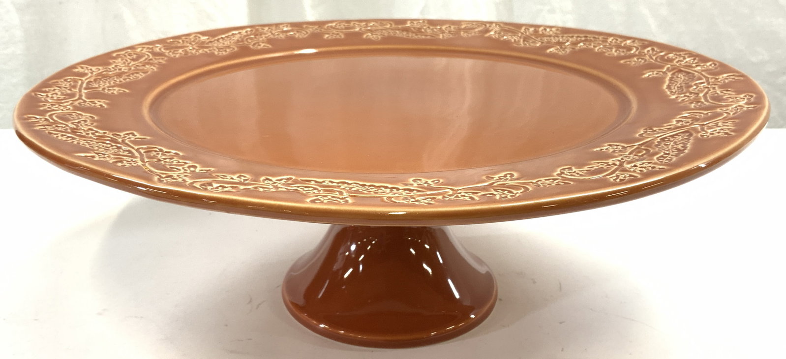 DANIEL CREMIEUX France Stoneware Cake Stand: Underside is trademarked DANIEL CREMIEUX FRANCE. Cake stand is raw sienna toned. Edges have vine and leaf. Cake stand is pedestaled. Piece measures approximately 13 inches diameter 4.5 inches tall. Ca