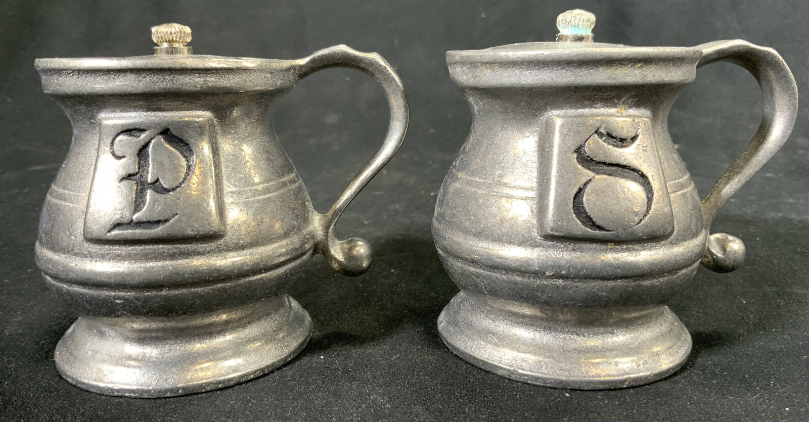Vintage Pewter Salt & Pepper Shakers: Lot includes 1 salt and 1 pepper shaker. Each are silver toned and pewter. One monogrammed S the other monogrammed P. Each have curled handles. Shakers each measure approximately 3 inches tall 3.5 inc