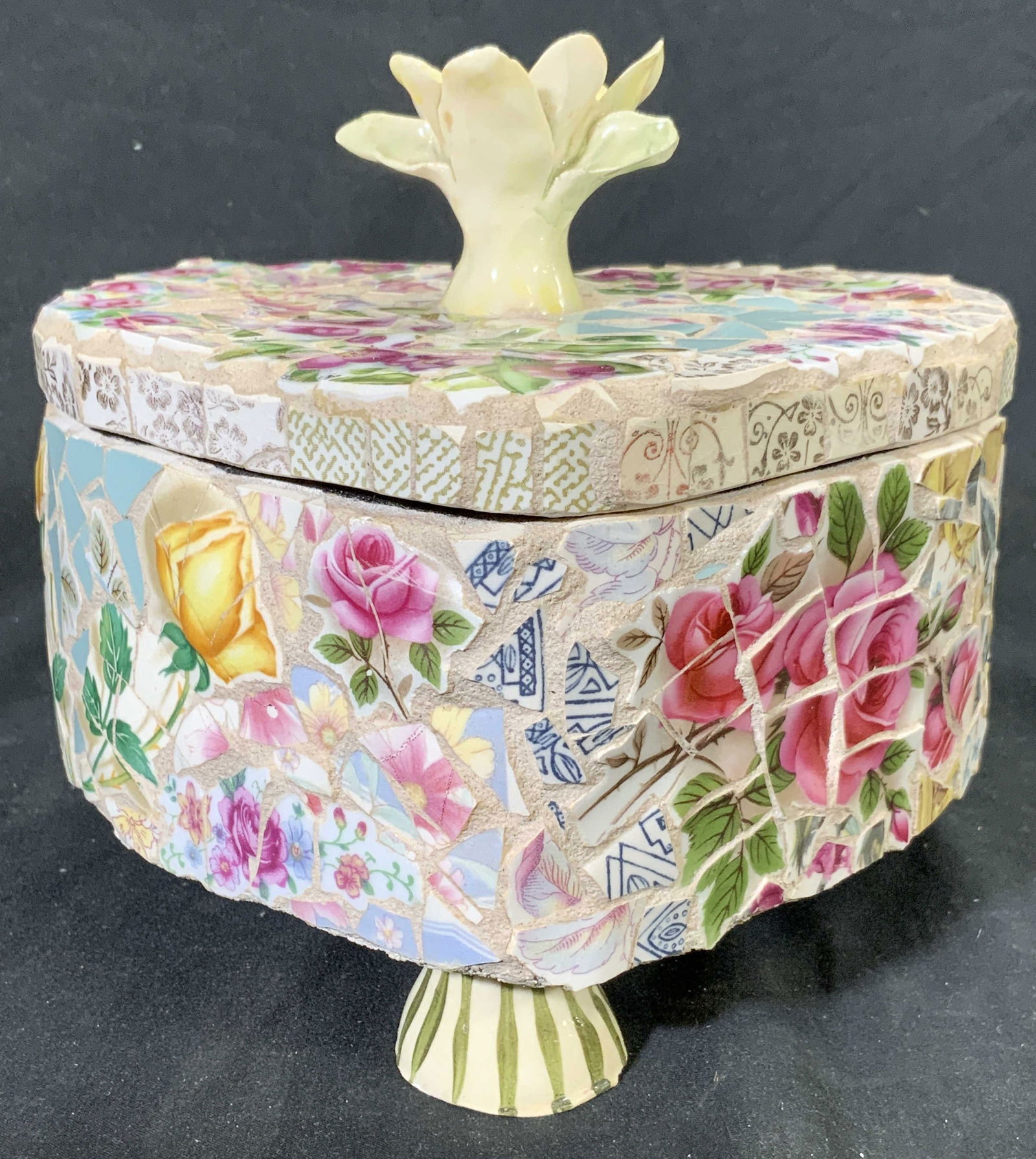 COLLETT Porc Mosaic Footed Heart Box W Lid CANADA: Lid handle reads COLLETT. Tag on underside reads MADE IN CANADA. Box is porcelain mosaic. Piece has intricate multi toned floral and leaf detail. Box includes lid. Lid has floral form handle. Box has