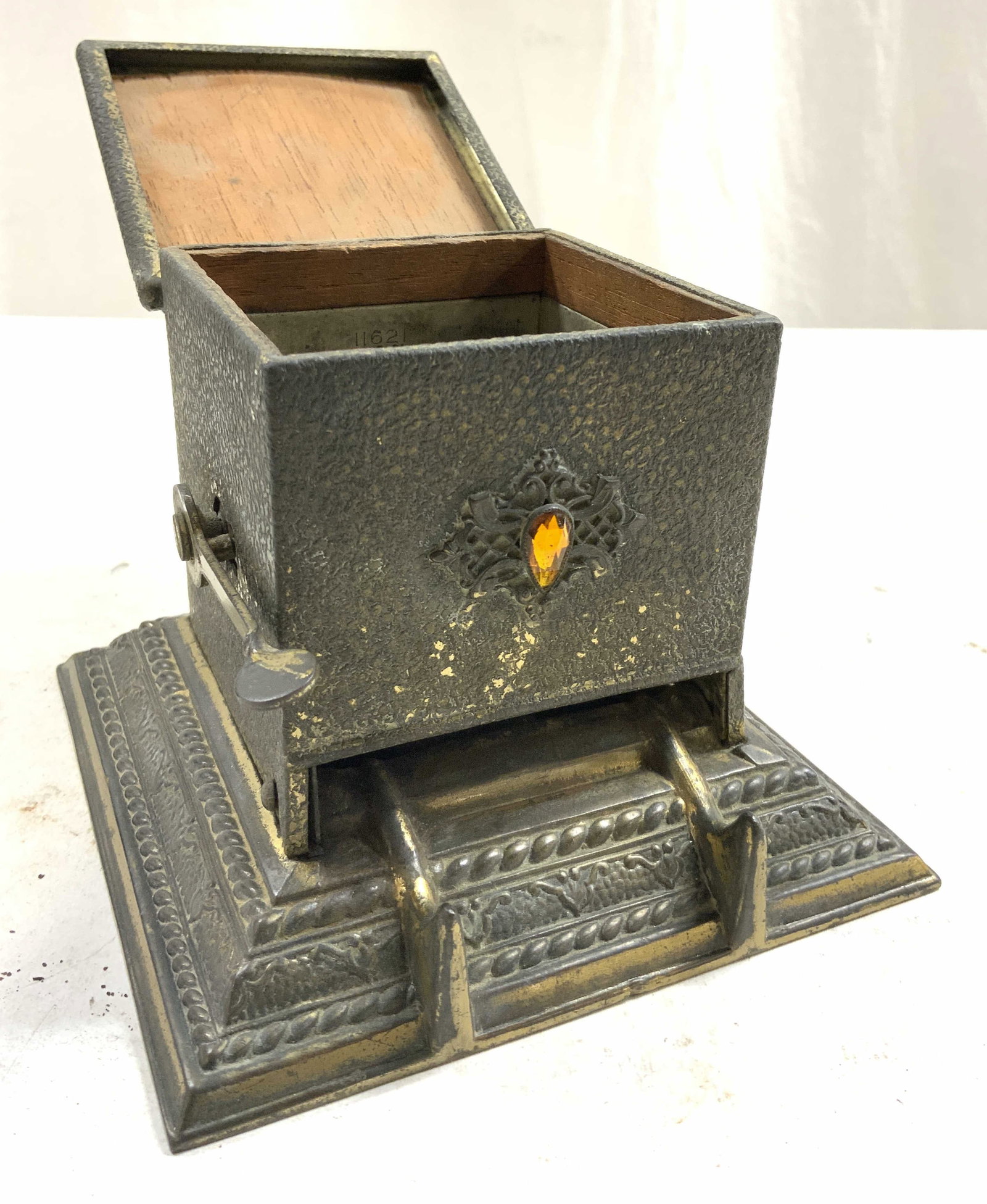 Antique Art Deco Gilt Metal Cig Dispenser W Lid: Interior is inscribed THE ART METAL WKS 11621. Piece appears to be antique possibly vintage. Dispenser is gilt metal possibly gilt bronze, possibly brass. Piece has purple & orange toned rhinestones, 