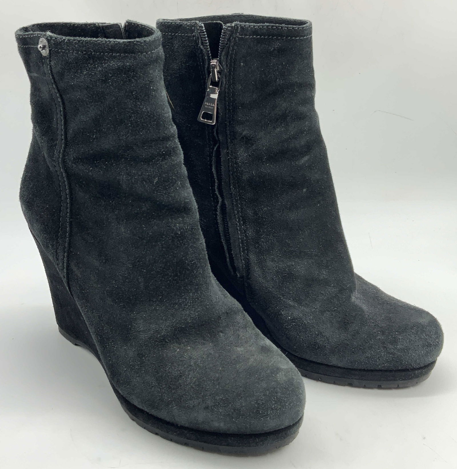 Prada Suede Wedge Heeled Ankle Boots: Marked on interior, Prada. Also marked in zippers. Black toned suede wedge heeled ankle booties. Marked 35 on interior lining. Approx 8.25 inches tall, with wedges being 3.75 inches tall and soles of