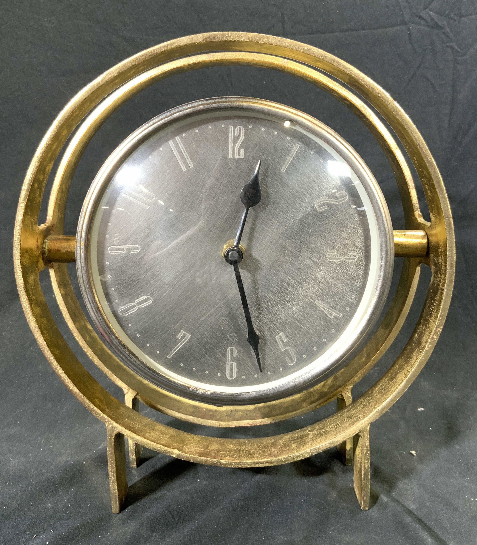 Gilt Metal Rotating Mantel Clock: Clock is gilt Metal. Piece is gold toned with silver toned clock face. Clock has black toned hands. Piece rotates on horizontally axis. Clock has 4 feet. Piece measures approximately 10 inches tall 9 