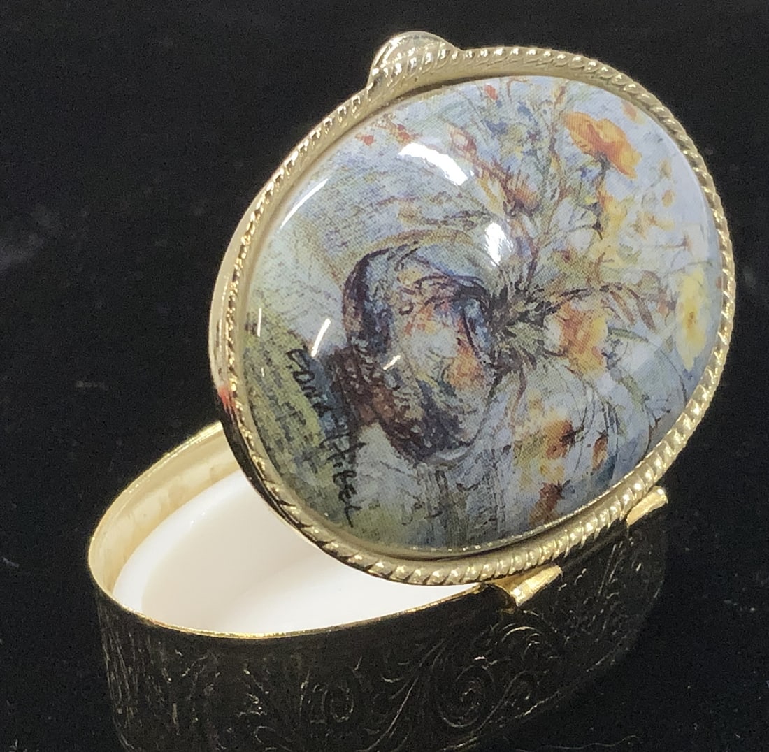 Hinged Pill Box w Edna Hibel Floral Lid, Italy: Medium size Pill box bought and made in Italy. These pill boxes are only found in Italy. Hinged lid, Gold Tone chased scrolled Metal, transfer print of still life flowers in a vase ( signed) by Artist