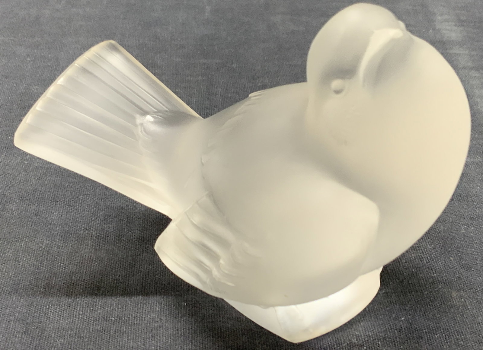 Lalique Sgd Frosted Crystal Bird Figure, France: Hand signed Lalique France. Frosted figure of a bird with tucked in wings and head looking up. Approx 3.25 inches tall and 4 inches long. Minor wearing to figure, some scratches observed. Lalique sign