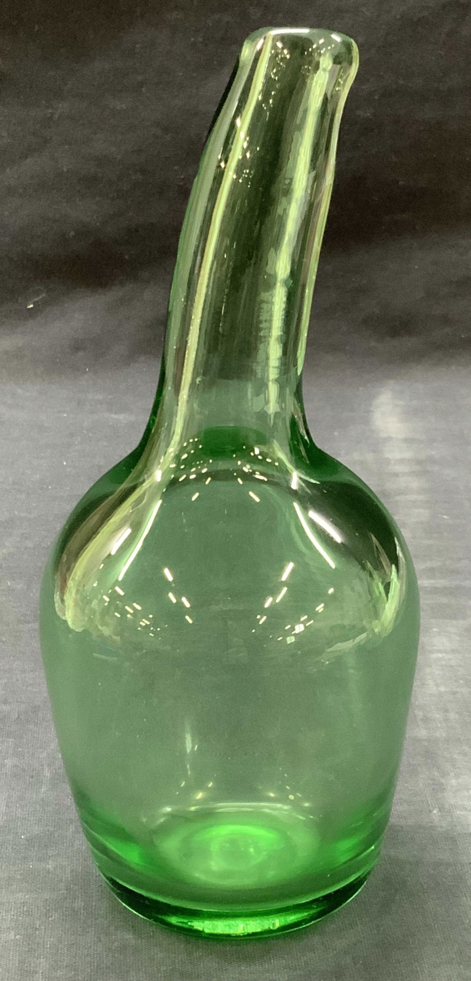 Hand Blown Emerald Art Glass Bottle: Hand blown art glass emerald toned bottle with curved neck. Approx 7.25 inches tall. Minor wearing to underside of bottle. Scratches observed. Hand blown glass, glass bottle, colored glass, hand blown