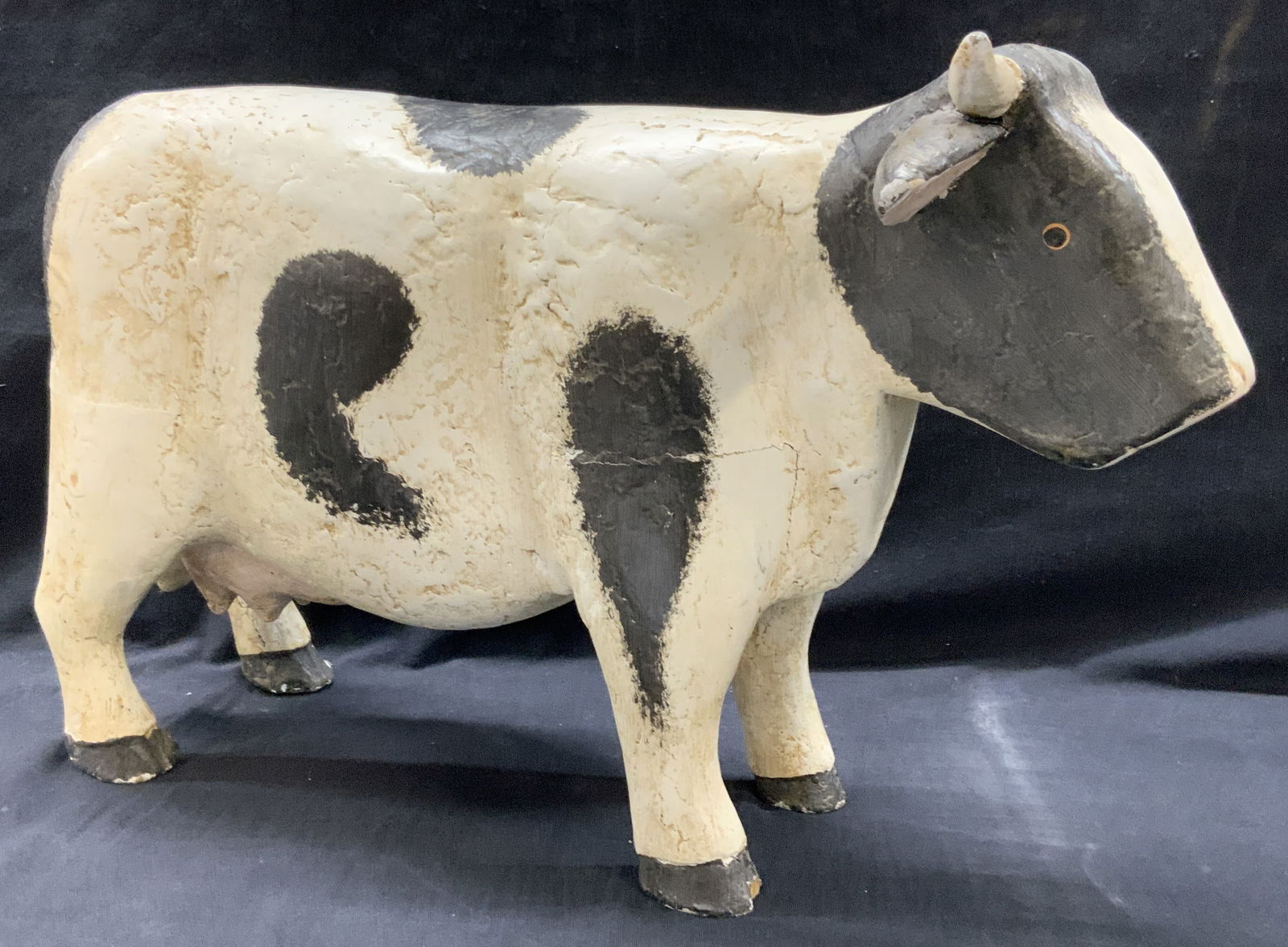 Hand Painted Folk Art Wooden Cow Figural: Wooden crafted folk art cow figure, hand painted with black and white throughout. Approx 11 inches tall and 17 inches long and 4 inches wide. Evident cracking to wood and losses to ears. Cow figures,