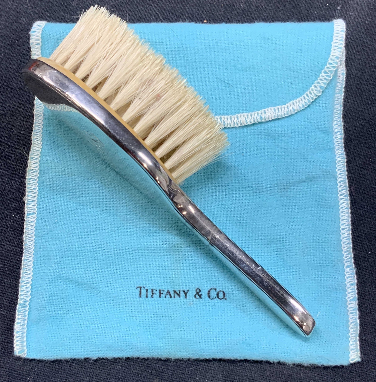 Tiffany&Co Vintage Sterling Silver Brush W DustBag: Marked Tiffany & co and shaped with the lion and anchor. Monogrammed on backside with initials, GSJ possibly, with off white bristles affixed to a wooden insert. Approx 5.75 inches long. Comes with bl