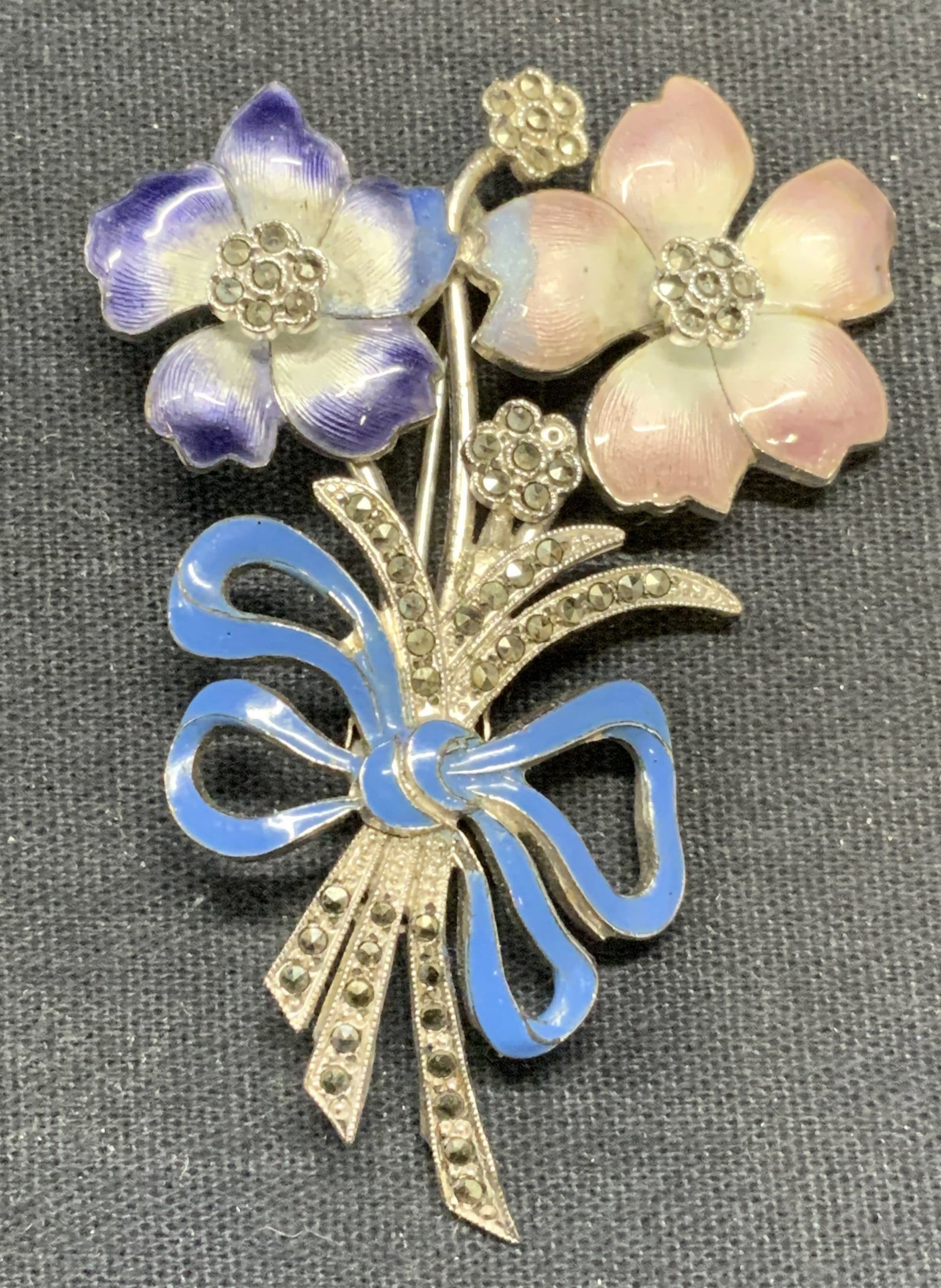 Sterling Silver Enamel Marcasite Flower Brooch: Sterling silver flower brooch with pink, purple, and blue enamel and marcasite decoration. Marked sterling to underside. Measures approx. 2 3/8 x 1.75 inches. Total weight 18 grams. Some scratching ob