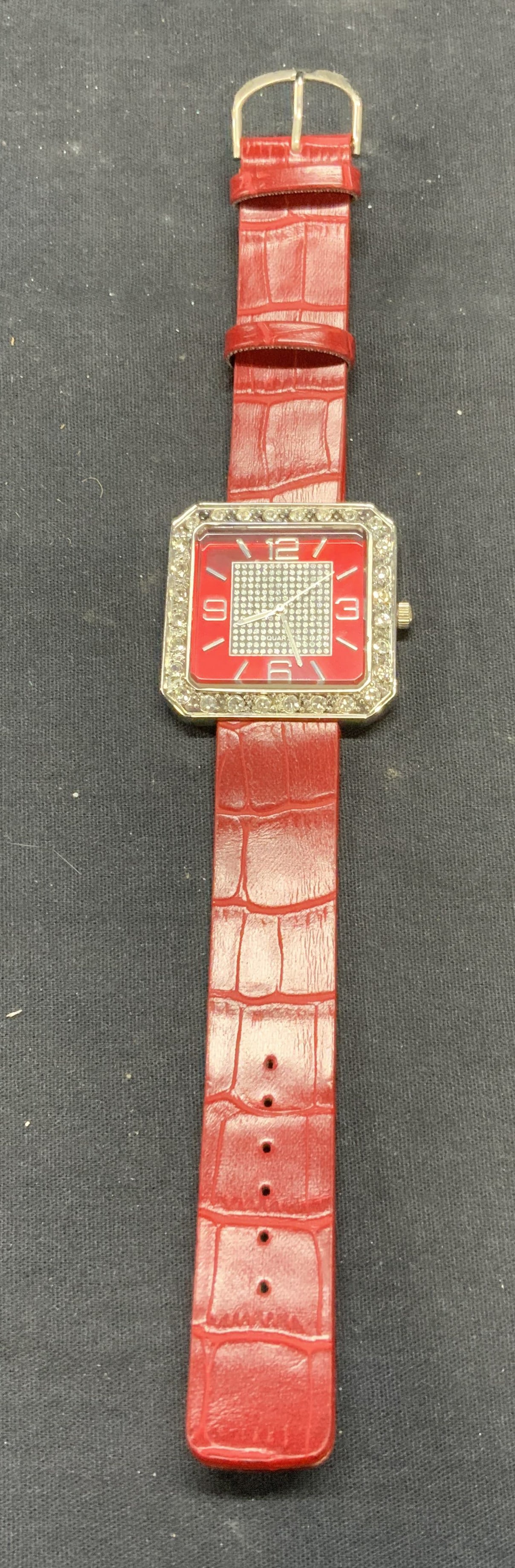 Japan Movement Red Leather Crystal Watch: Stainless steel crystal decorated watch with red leather strap. Marked Japan movement to underside. Face measures approx. 1 5/8 x 1 5/8 inches. Watch measures approx. 8.75 inches long. Not tested for 