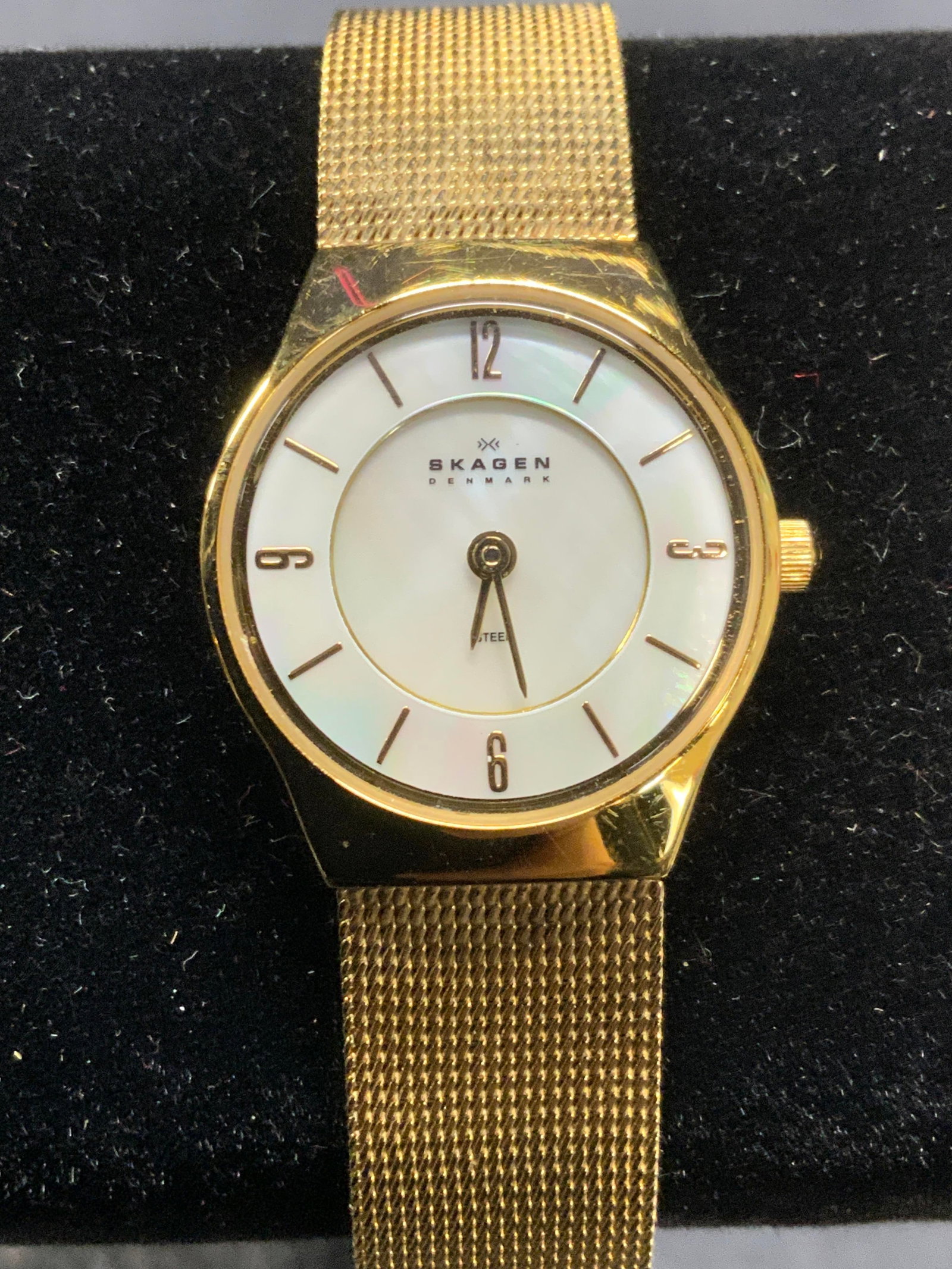 Skagen Denmark Gold Tone Mother of Pearl Watch: Skagen Denmark gold tone stainless steel watch with bracelet strap and mother of pearl face. Signed on watch face. Strap measures approx. 7.75 inches long. Some scratching observed. Estate jewelry, co