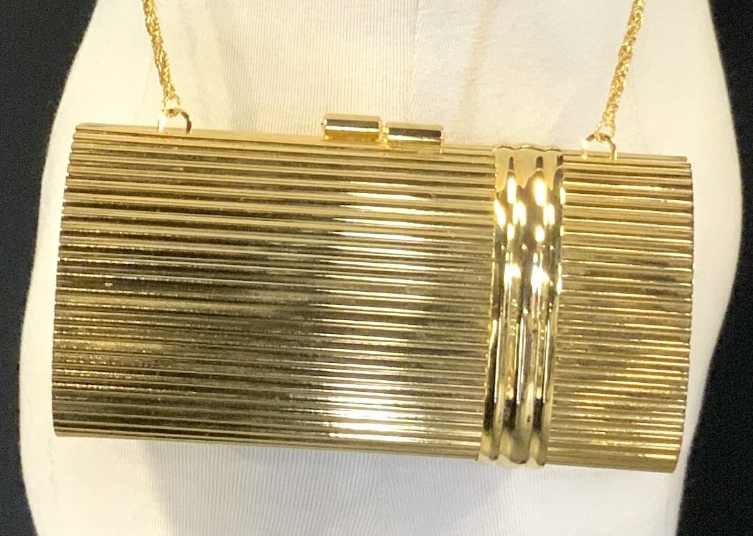 AMANDAS NEW YORK Gilt Metal Clutch: Tag in interior reads Amandas New York. Clutch has gilt metal exterior. Piece has twist chain link. Interior is black toned, appears to be line in crushed velvet. Clutch has kiss clasp. Measures appro