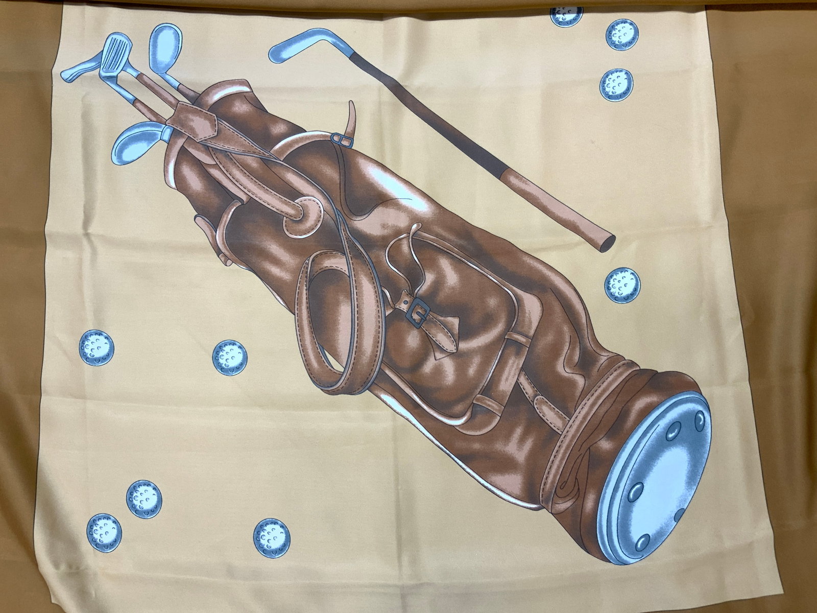 Golf Caddy Silk Scarf: Silk scarf with Images of a golf case with sticks in the case and golf balls on the corners and the boarder of the scarf resembling golf clubs. Approx 35 x 34 inches, minor wearing to edge to scarf Go