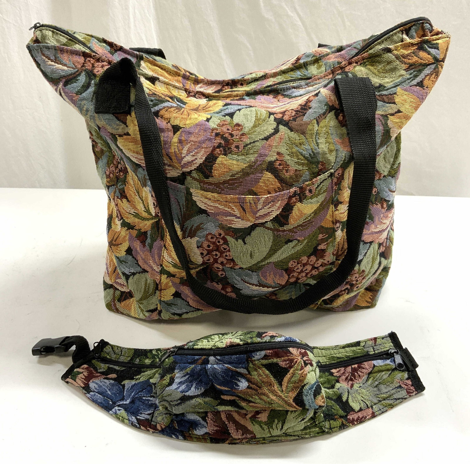 TRADE ROUTES INC Needlepoint Tote & Fanny Pack: Tag reads TRADE ROUTES INC MADE IN TURKEY. Lot includes 1 tote & 1 Fanny pack. Each piece has intricate multi toned floral & leaf needlepoint detail. Each bag has black toned straps and zippers. Tote 