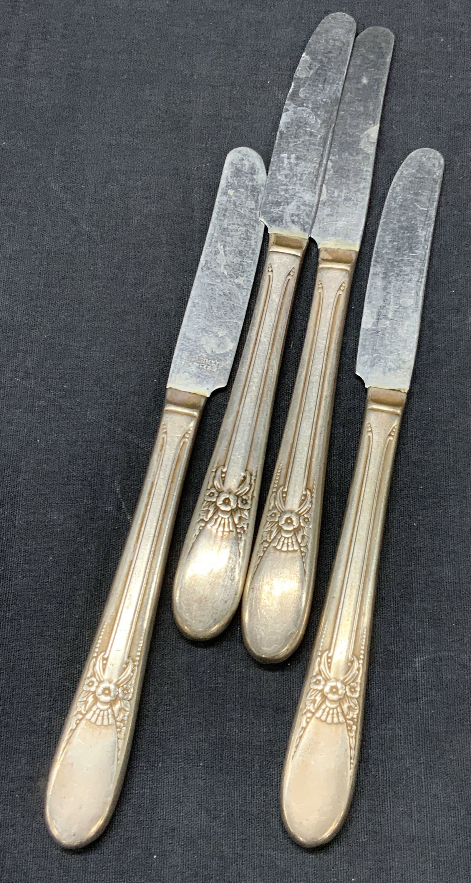 WM Rogers Stainless Steel & Sterling Knives: Set of 4 wm Roger butter knives, marked stainless steel on blades and sterling silver handles. Tester positive for sterling using Puritest metal tester. Handles adorn with flower motifs on handles, ap