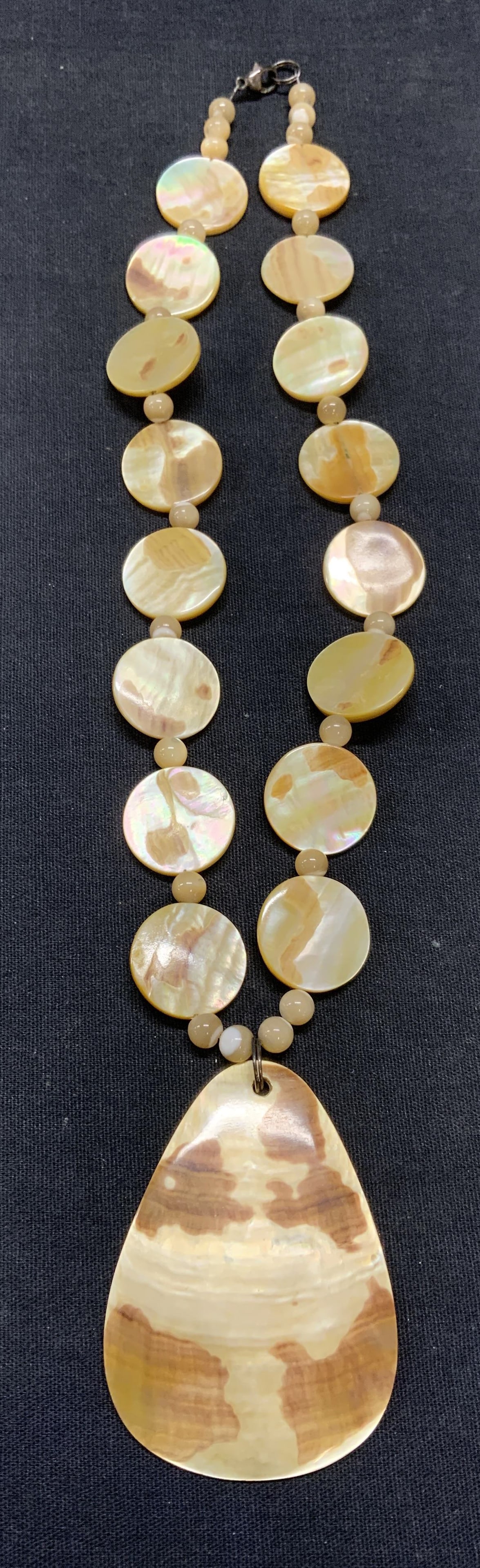 Mother of Pearl Beaded Pendant Necklace: Mother of pearl necklace with round seed beads, flat disc beads, and pendant. Drop length approx. 8.75 inches. Pendant measures approx. 2.5 x 1.5 inches. Some scratching observed. Estate jewelry, cost