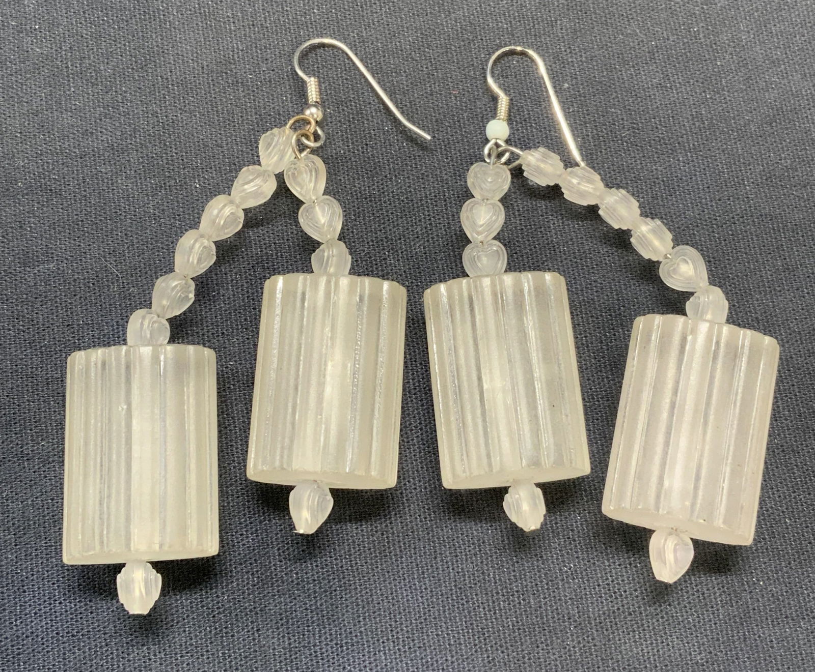 Opaque White Lucite Beaded Earrings: Opaque white lucite beaded earrings. Heart shaped and ribbed cylindrical shaped beads. Hook backing. Measure approx. 2.5 inches long. Some scratching observed. Estate jewelry, costume jewelry, cocktai