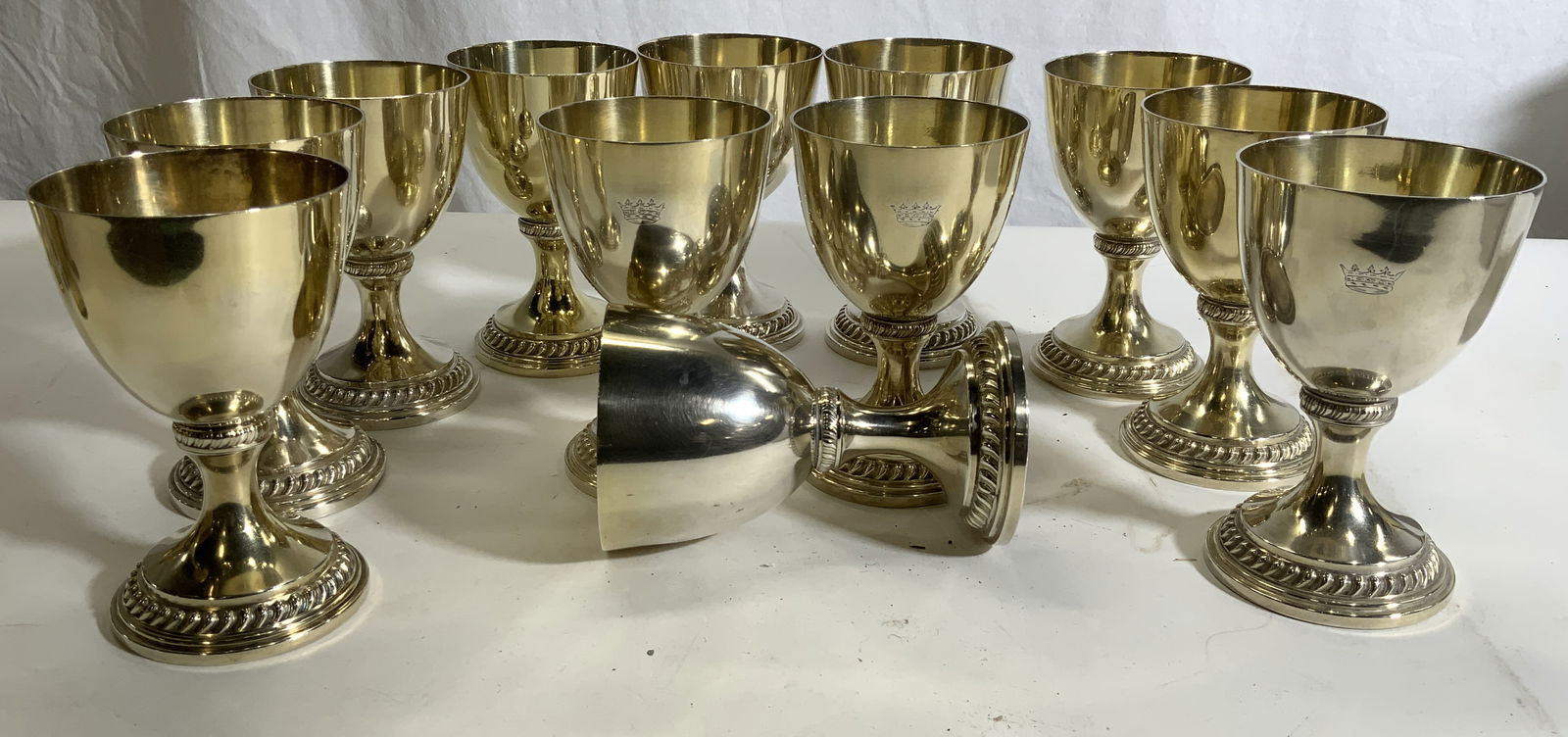 Set 12 Silver Plated Gold Wash Goblets: Vintage Silver plate goblets with a chased crown and trademark on underside. 6 x 3.75 in. Possibly Mid century. Gold wash cup interior and decorative design on stem and base. Minor surface wear, some