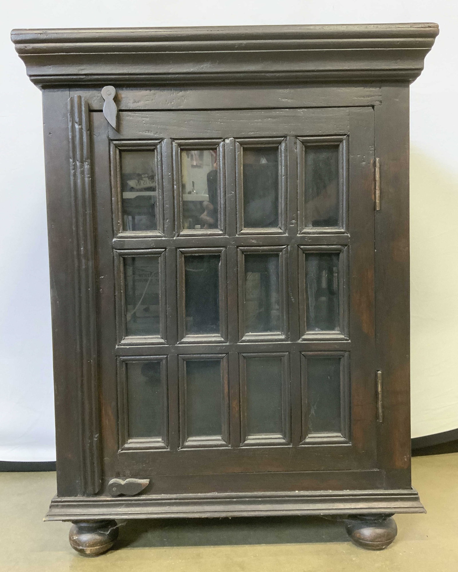 Vintage Windowed Wooden Cabinet Dark Brown: Cabinet is vintage and wooden. Piece has carved wooden bun feet. Cabinet has windowed door. Piece is dark brown toned. Cabinet measures approximately 28 inches tall 21 inches wide 13.5 inches deep. Ca