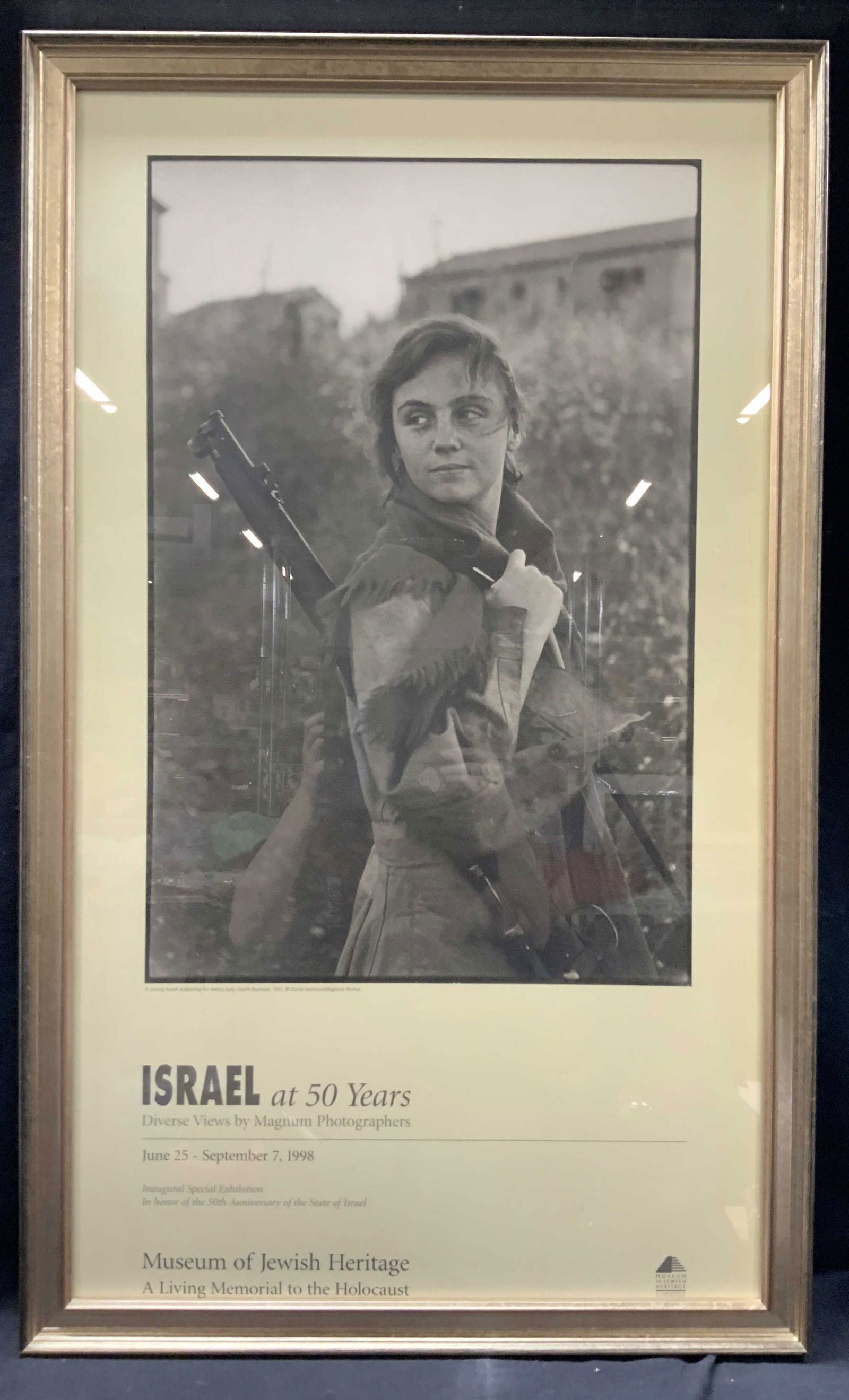Israel At 50 Years Exhibit Advert Litho, 1998.: Advert lithograph reading Israel at 50 years, diverse views by Magnum photographers. 1998, at the museum of Jewish heritage. Depicts a woman soldier by David Seymour. Frame in a silver leafed wooden f