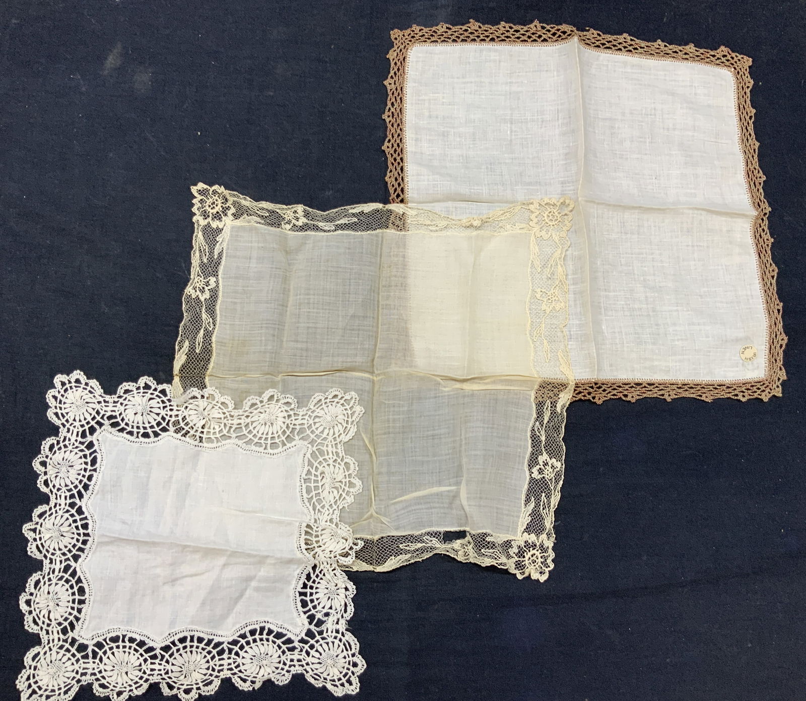 Lot 3 Vintage Lace Linens: Lot of 3 vintage assorted linens. 1 marked Irish linen with red and green crocheted edges, 1 off white linen napkin with hand crafted lace edges with floral motifs and 1 off white linens with off whit