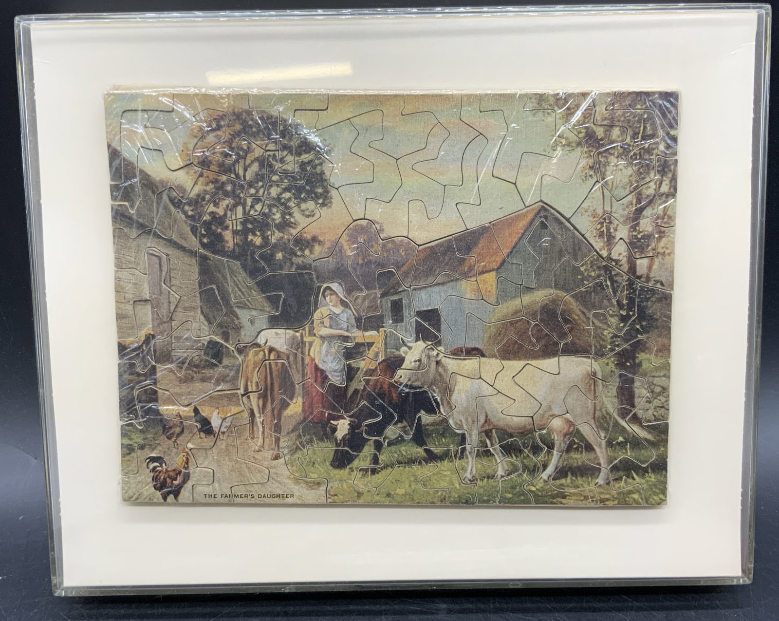 THE FARMERS DAUGHTER Puzzle Framed: A puzzle featuring a young woman and farm animals in a nature setting. Puzzle titled THE FARMERS DAUGHTER. Puzzle is wrapped in plastic and comes in a Display Frame Case measures approx. 8.25L x 10.25