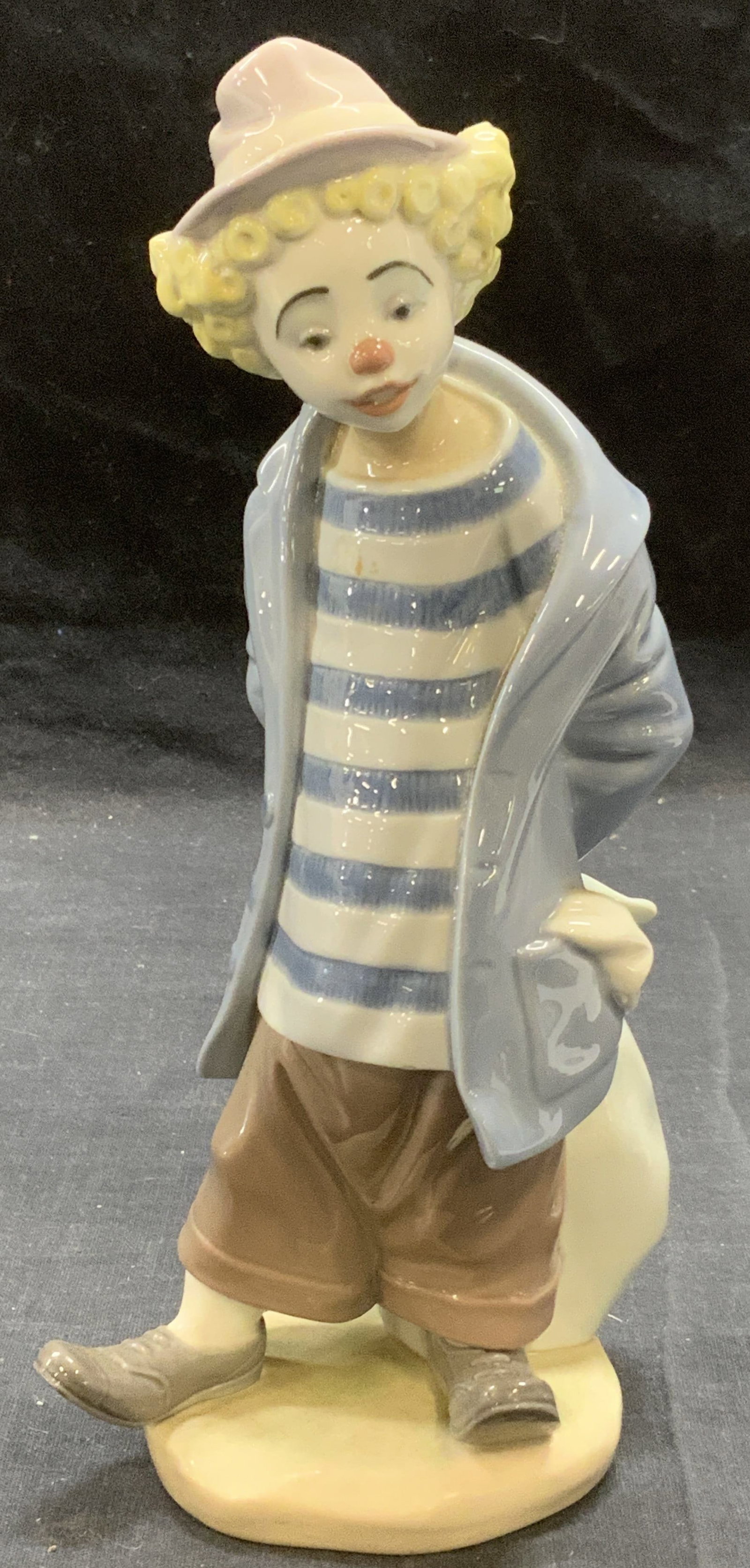 LLADRO Porcelain Little Traveler Clown Figural: Lladro #7602 Little Traveler Clown porcelain figurine. Made in Spain. In good condition. Trademarked to underside. Measures approx. 3.5 x 3.25 x 8.5 inches. Marked 1986 Collectors Society to underside