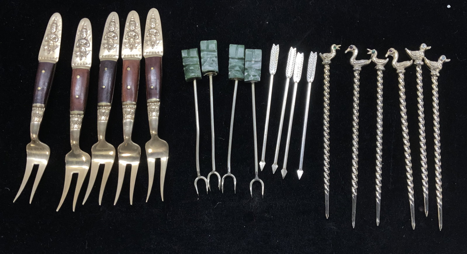 19 Cocktail Picks & Forks, S Samran Thai, England: 4 distinct sets of cocktail picks and forks. Set 5 S. Samran Thailand Co 2 prong brass and wood forks, 4.5 in. Long. In original box. Embossed decor with bodhisattva handle tips. Set 4 carved natural 
