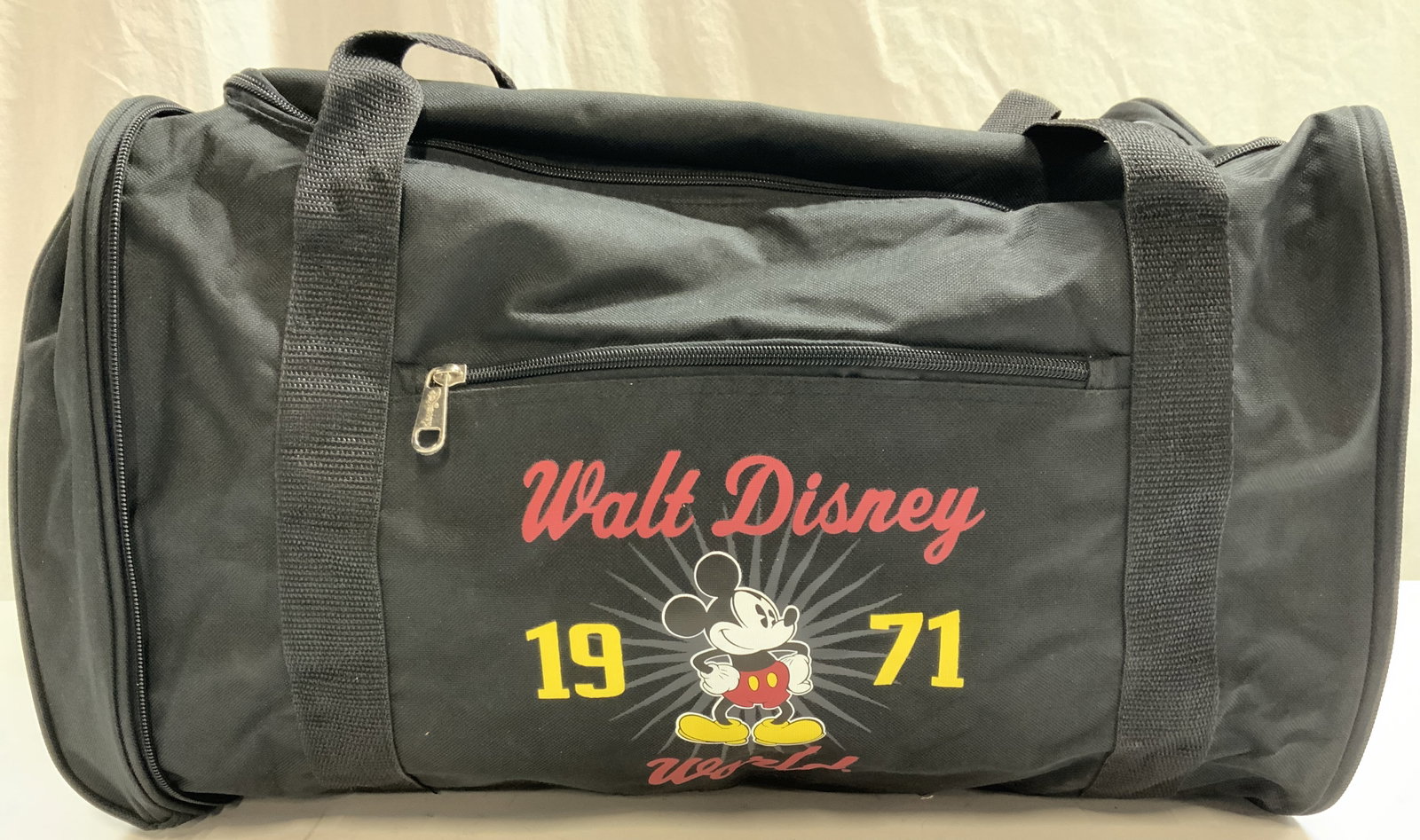 1971 Walt Disney World Canvas Duffel Bag: Marked on exterior Walt Disney world, 1971 with an image of Mickey Moise. Black canvas duffel bag with top handle. Marked on interior tag, Walt Disney parks, authentic, original. Approx 12 inches tall