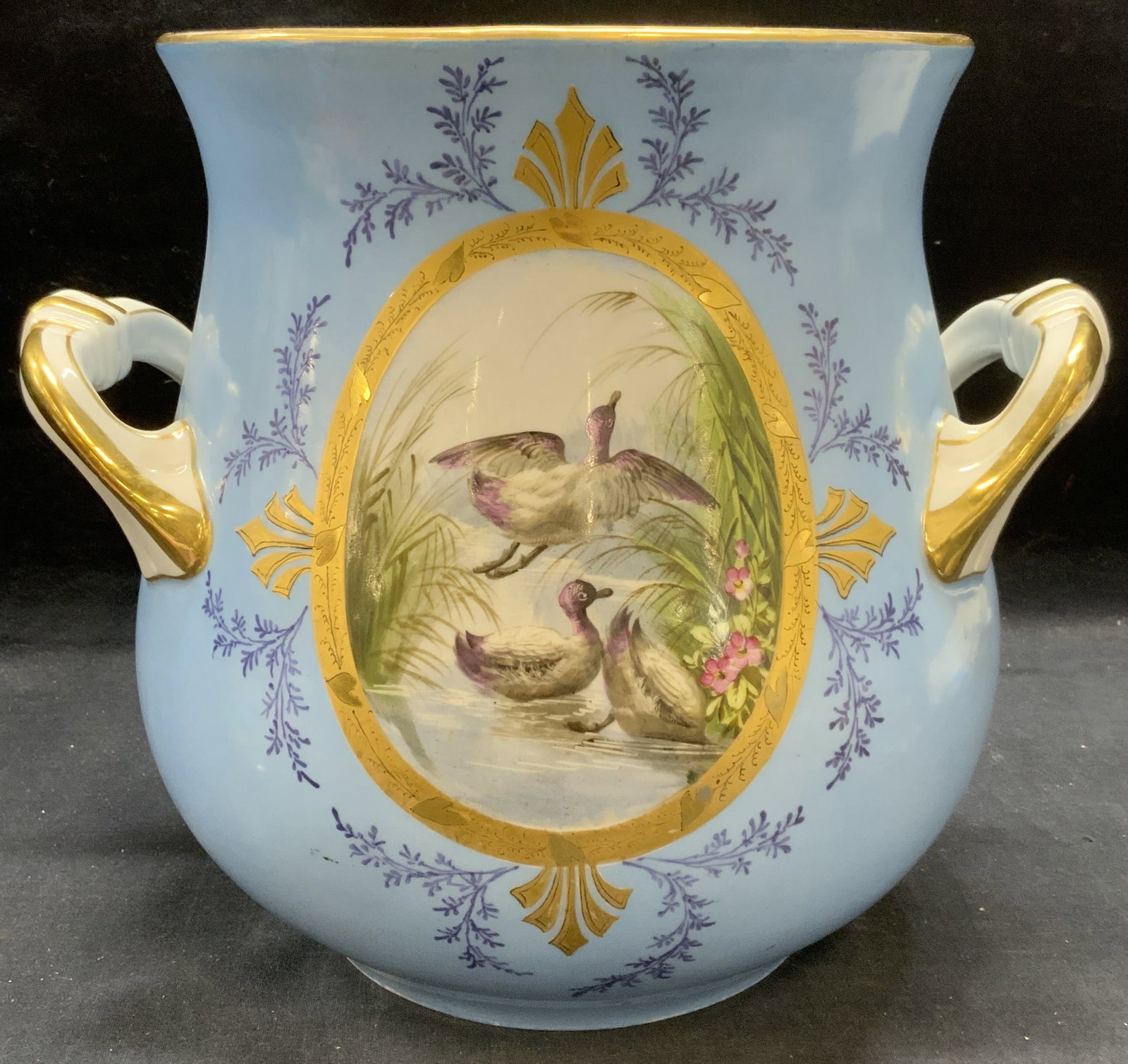 Vintage Gilt Porcelain Duck Urn: Vintage, possibly antique, porcelain urn. White and blue with hand painted duck motif and gilt decoration. Measures approx. 12 x 10.25 inches. Some surface wear including scratching observed. Porcelai