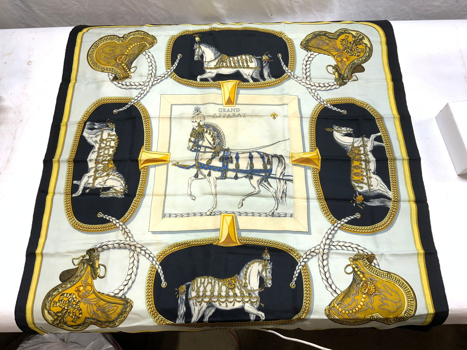 HERMES PARIS/Jacques Eudel Grand Apparat Scarf: Hermes Grand Apparat 90 scarf by Artist Jacques Eudel in silk twill with hand rolled edges. Black dark border, pale blue center and details in gold, black, and white. Signed Hermes Paris and Signed Ja