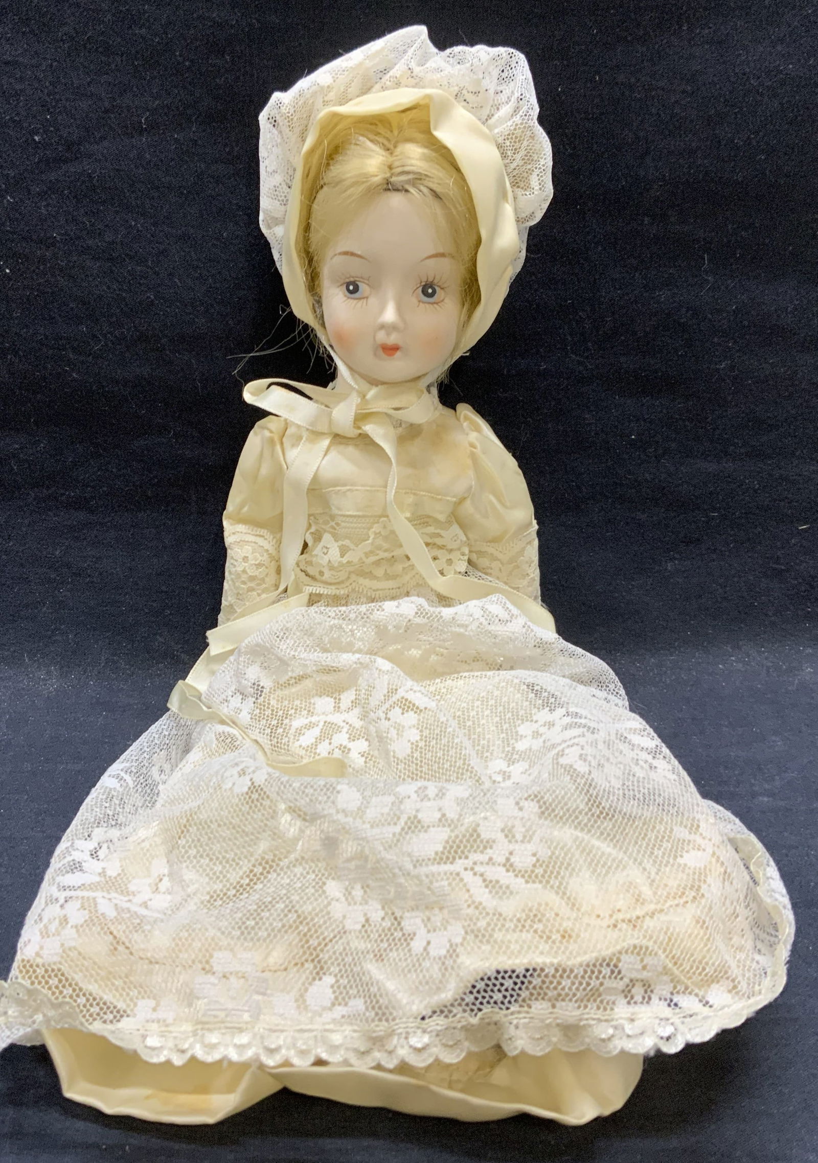 Vintage Porcelain Doll w White Lace Dress: Vintage doll with fabric body, porcelain head and limbs. Hand painted face. White lace dress and bonnet. Measures approx. 14 inches long. Some wear to material consistent with exposure. Doll, vintage