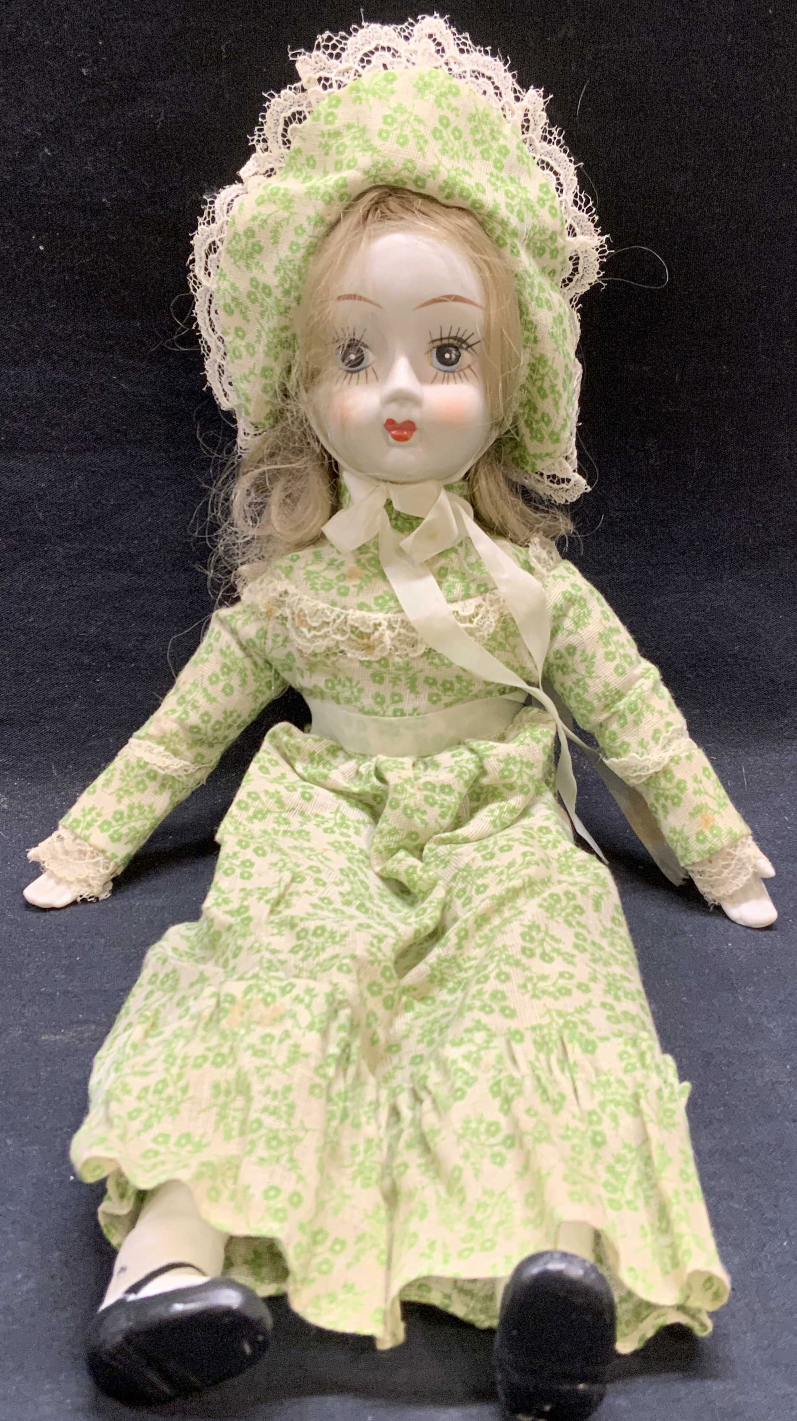 Vintage porcelain Doll w Green Floral Dress: Vintage doll with fabric body, porcelain head and limbs. Hand painted face. green floral print dress and bonnet. Measures approx. 15 inches long. Some wear to material consistent with exposure. Doll,