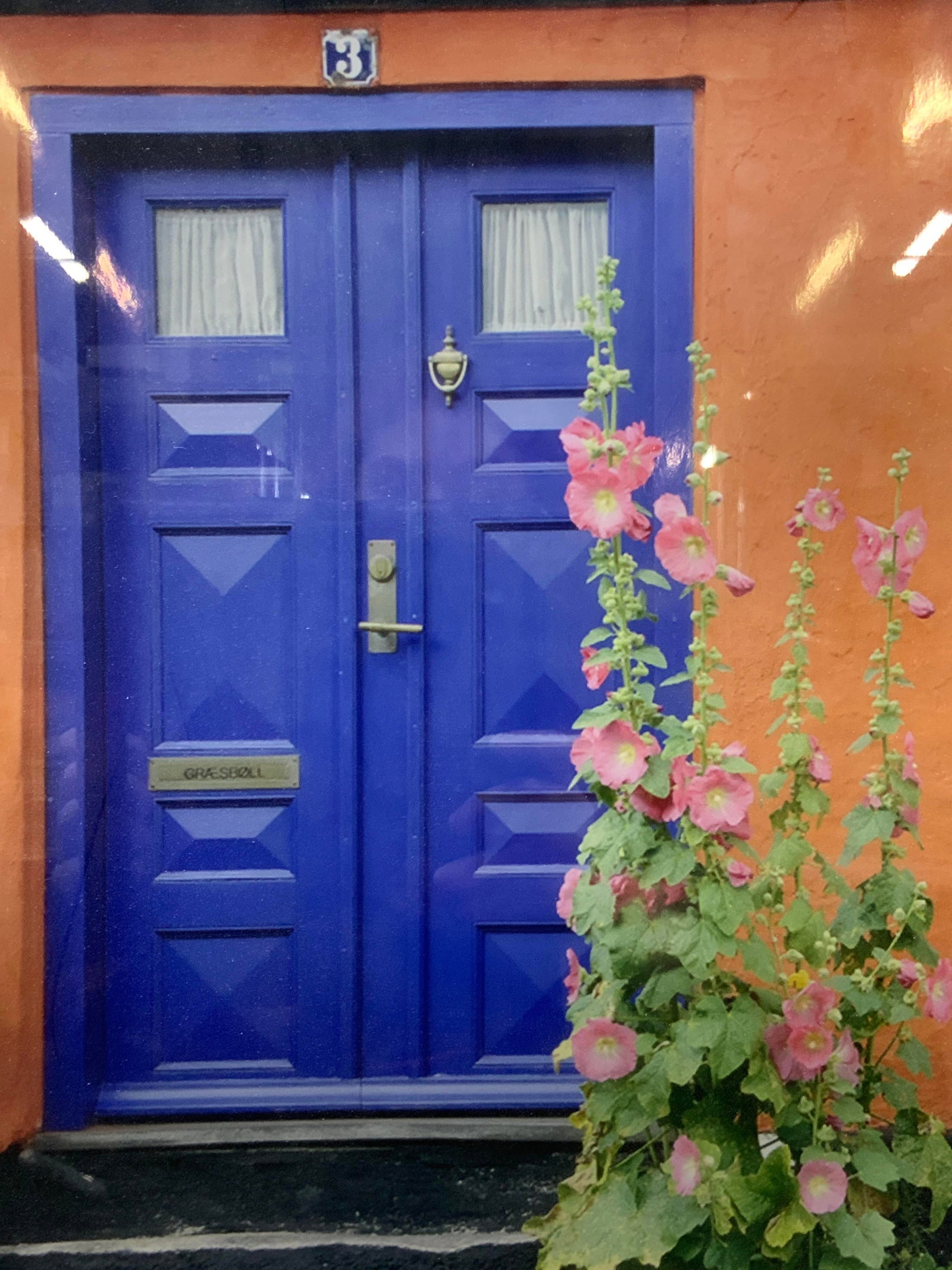Sgd Blue Door Photograph: Signed on lower right margin, depicts a blue toned door against an orange wall. Framed in a black metal frame with white mat board, approx 20 x 16 inches window measures 13.5 x 10 inches. Moderate wea
