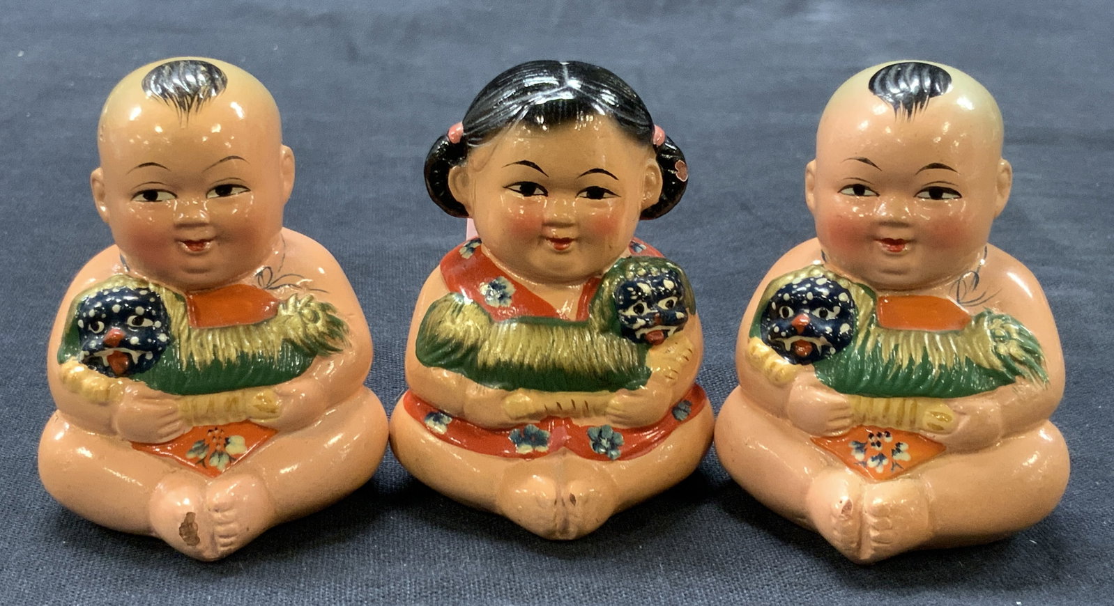 3 Asian Hand Painted Ceramic Baby Sharpeners: Lot of 3 hand painted ceramic babies with fu dogs in their arms, and pencil sharpeners on their backsides. Approx 2.25 inches tall and 1.75 inches wide. Moderate wearing to ceramics and loss to sharpe