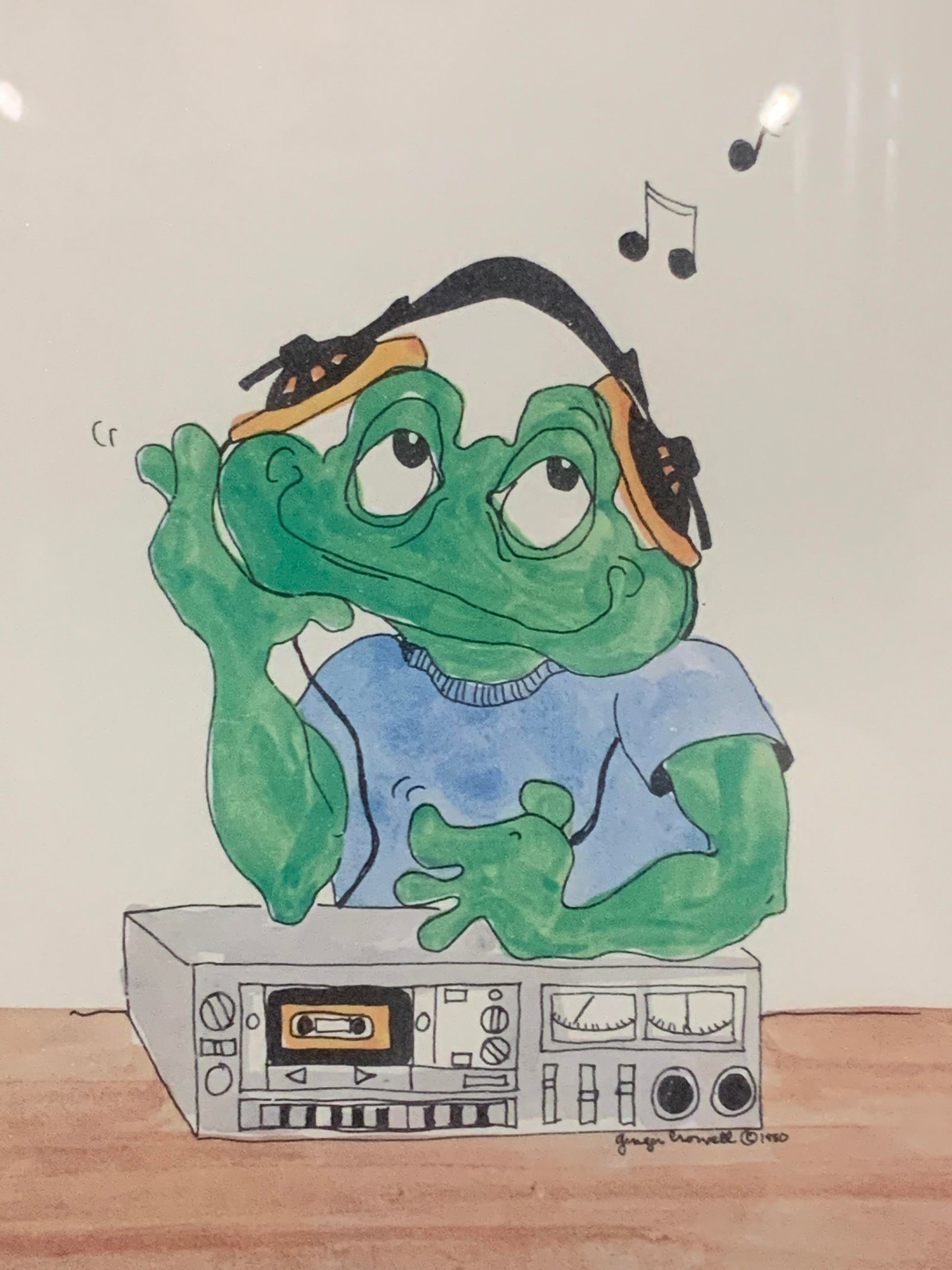 Marked Frog Drawing Lithograph: Marked on lower right corner with artist name, illegibly Depicts a frog with headphones on listening to a cassette player Framed in a silver toned metal frame with brown mat board, approx 14.5 x 11.5 