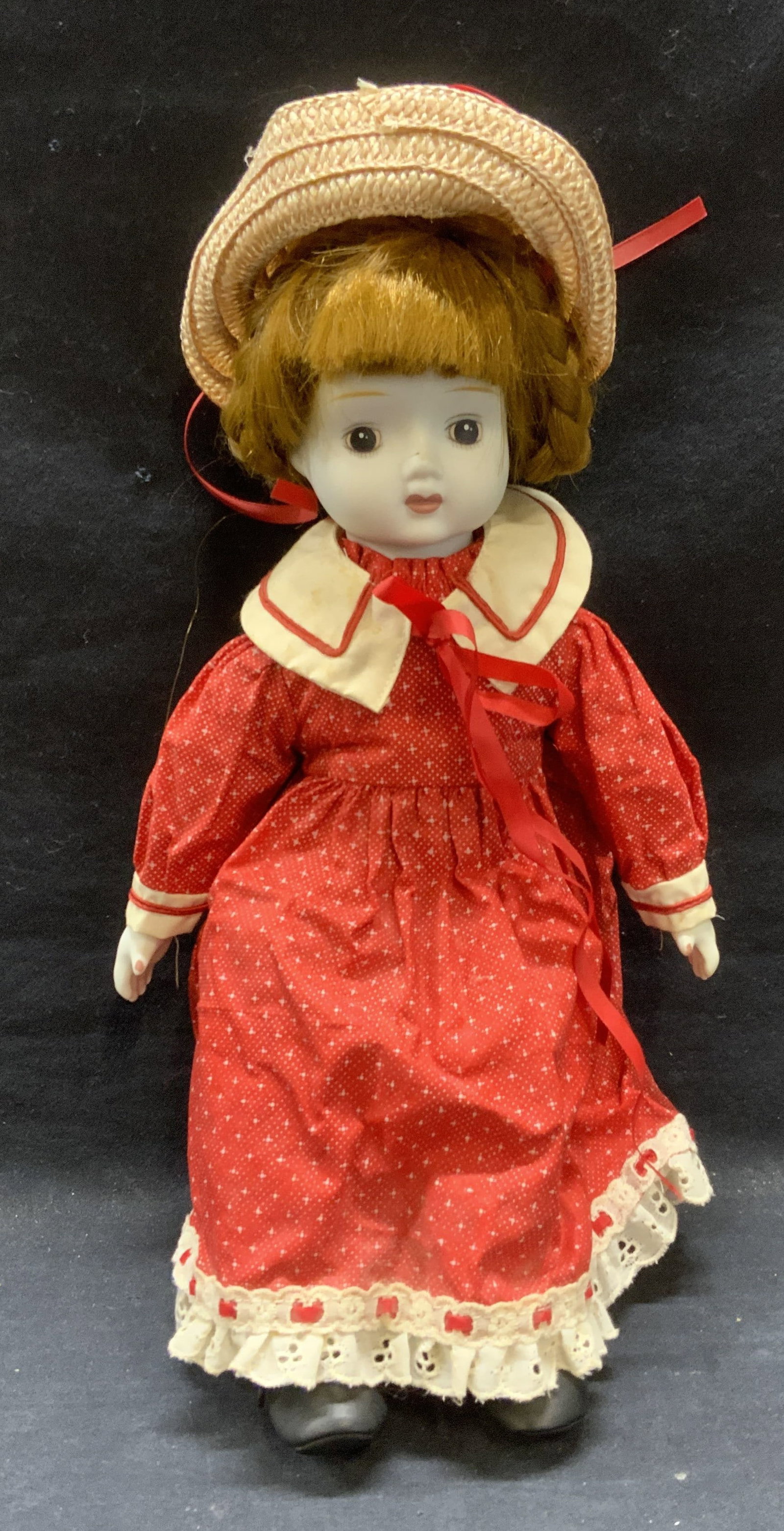 Vintage Porcelain Doll w Red Dress: Vintage porcelain doll with red dress and straw hat. Measures approx. 14 inches long. Some wear to material consistent with exposure. Doll, vintage doll, collectible doll, porcelain doll, toy, vintage