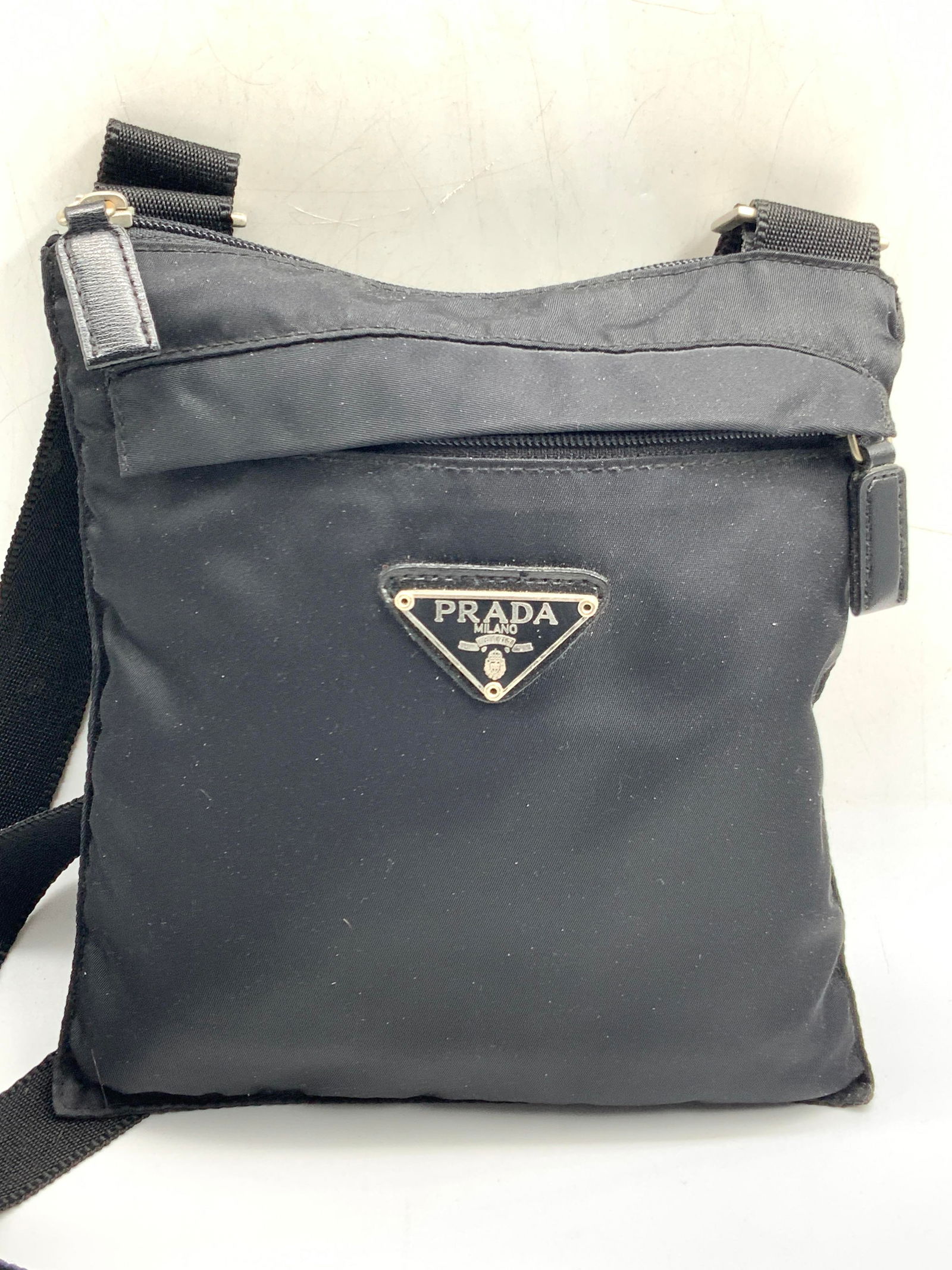 Prada Style Shoulder Bag: Prada style shoulder bag. Marked on plaque Prada, Milano. With wide shoulder strap and front and main zipper. Approx 9 x 8 inches and shoulder strap being 20 inches long. Minor wearing to exterior bag