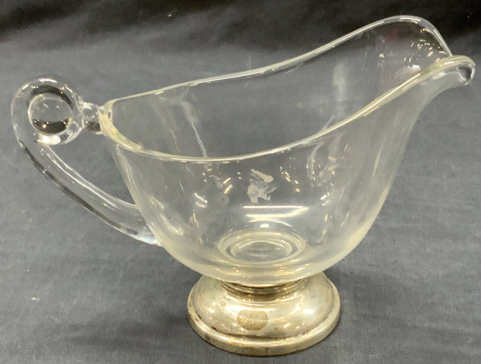 Sterling Silver Base Clear Glass Gravy Boat: Clear glass gravy boat with curled back handle sand lipped rim affixed to a sterling silver base. Approx 5 inches tall and 7 inches long. Total weight 11.03 ozt Evident discoloration to sterling base 