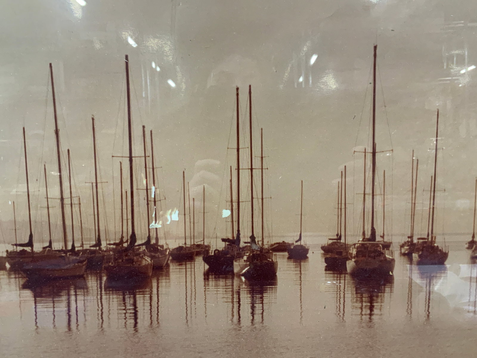 Sepia Tn Sail Boat Maritime Photograph: Sepia toned photograph of a cluster of boats on the water. Framed in a black and gold leafed wooden frame, approx 18.5 x 22.5 inches window measures 15.5 x 19.5 inches. Minor wearing to frame and mode